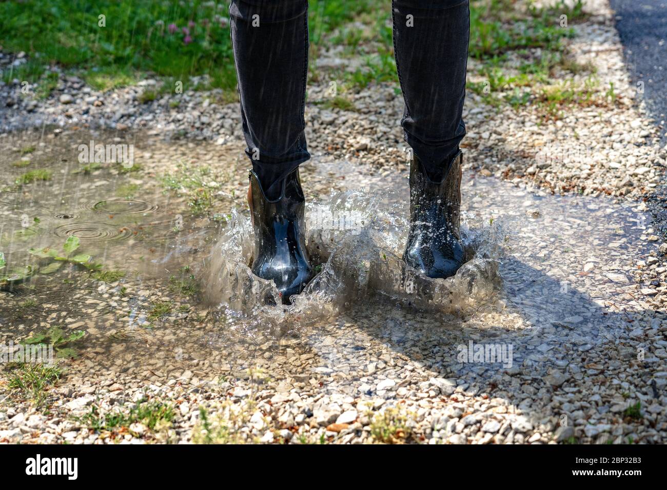 woman playing in a puddle heavy rain with bumboots on Stock Photo