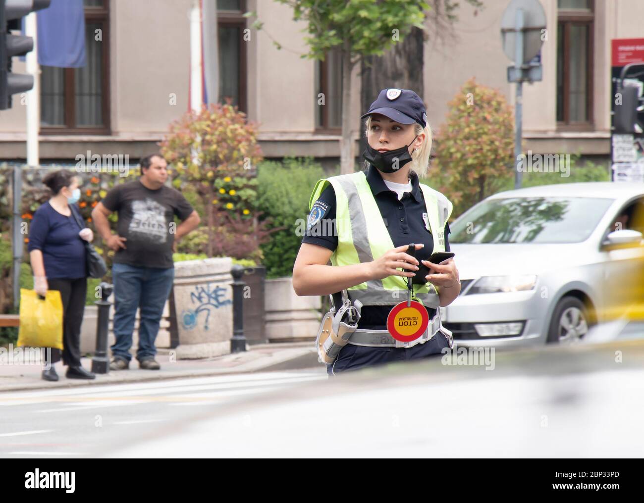Belgrade, Serbia - May 15, 2020: Policewoman on duty, standing in the intersection with traffic in motion blur Stock Photo
