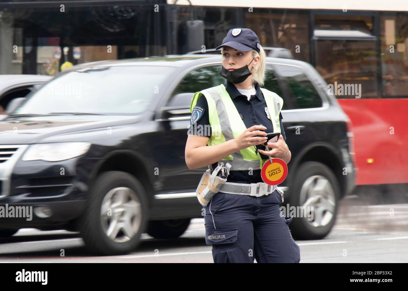 Belgrade, Serbia - May 15, 2020: Policewoman on duty, standing in the intersection with traffic in motion blur Stock Photo