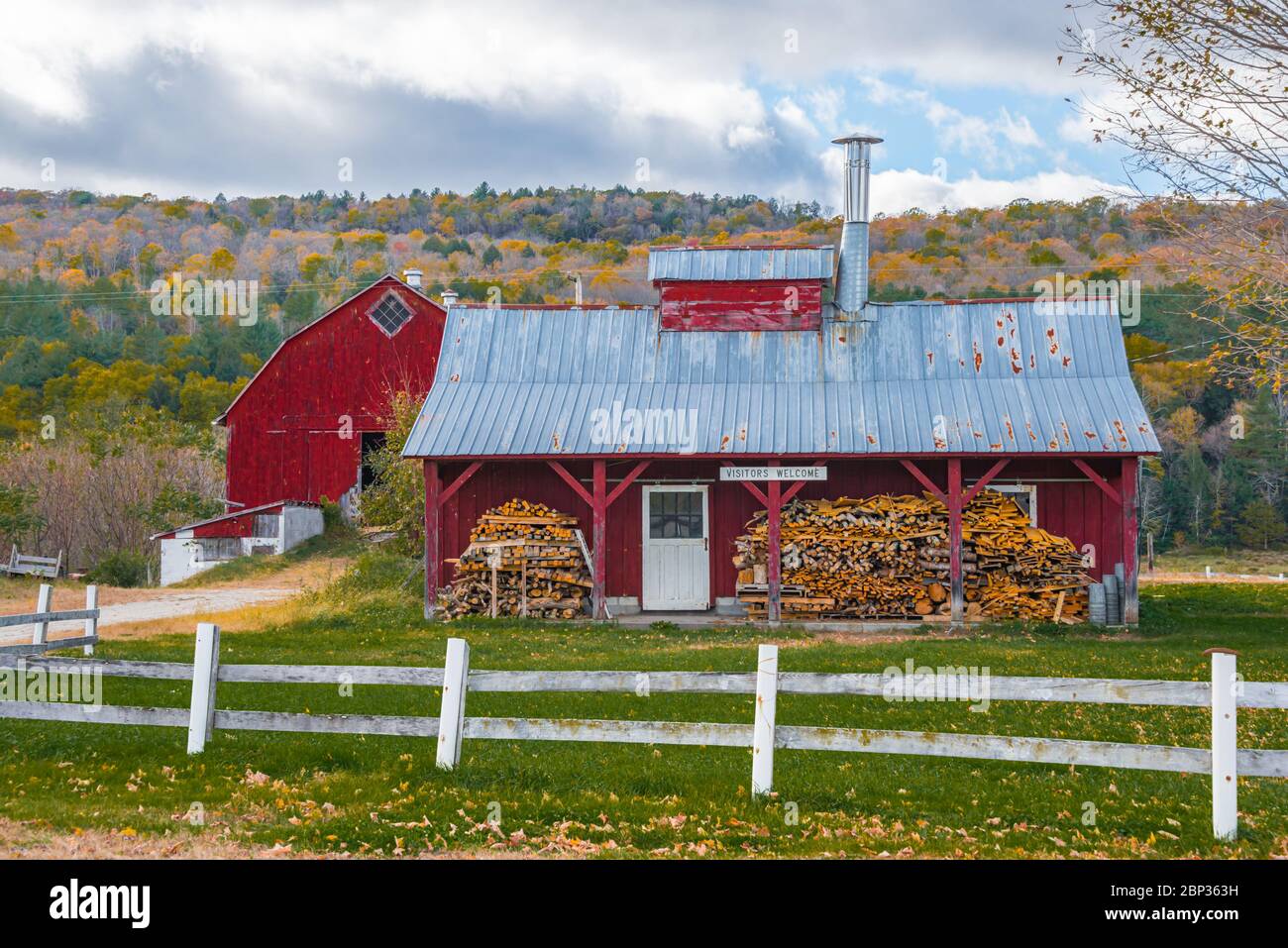 Stacked Wood in front of Red Sugarhouse & Barn, Weathersfield, Vermont Stock Photo