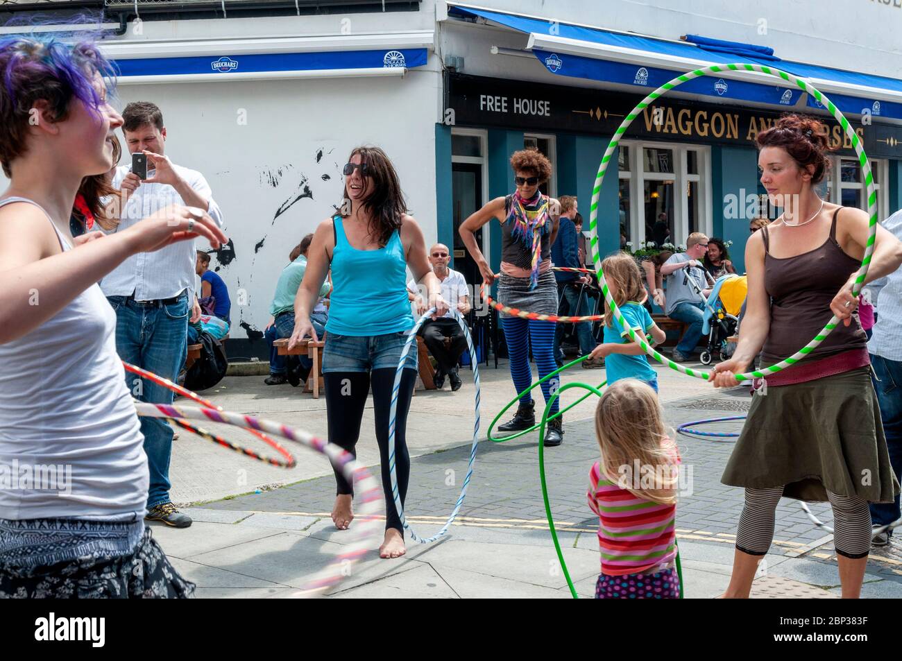 Women and young girls playing with hula hoops in the crowded streets during the Brighton Festival 2012 in Brighton, United Kingdom Stock Photo