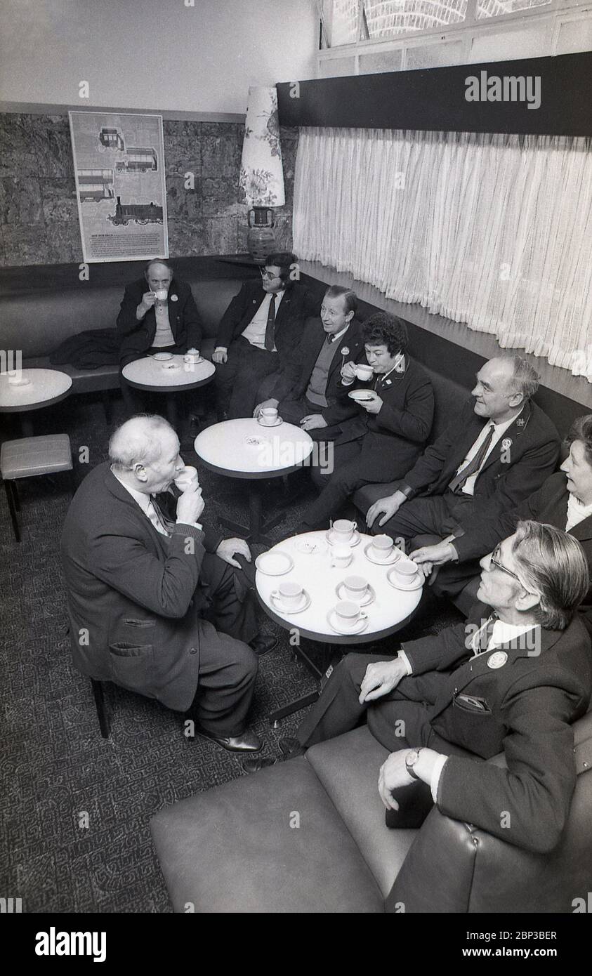 Interior picture showing uniformed bus workers sitting together in a rest room at New Cross bus depot, south east London, England, 1974. The bus crew are having a break, a cup of tea, a smoke and a chat with work colleagues. Orginally a tram depot, New Cross was converted into a bus depoet n 1952 and was one of the largest of London's bus garages. Stock Photo