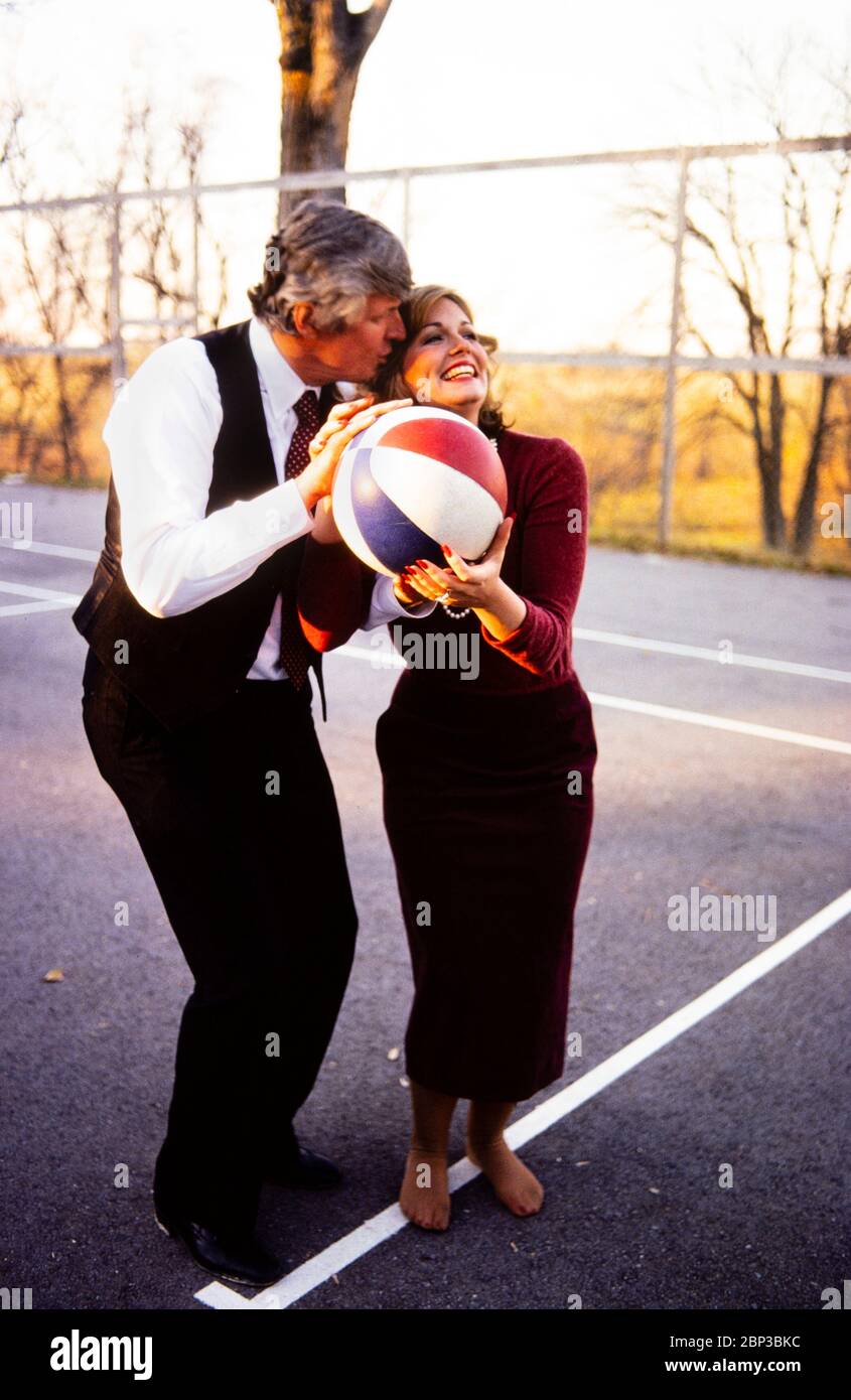 Phyllis George and new husband, Kentucky governor elect John Y Brown play a game of 'horse' on a basketball court at their home in Lexington. Brown is trying to distract his new bride by kissing and blowing in her ear. Phyllis Ann George was an American businesswoman, actress, and sportscaster. She was also Miss Texas 1970, Miss America 1971, and the First Lady of Kentucky from 1979 to 1983. Ms. George died, aged 70, of complications from Polycythemia vera on May 14, 2020 in Lexington, Kentucky. Stock Photo