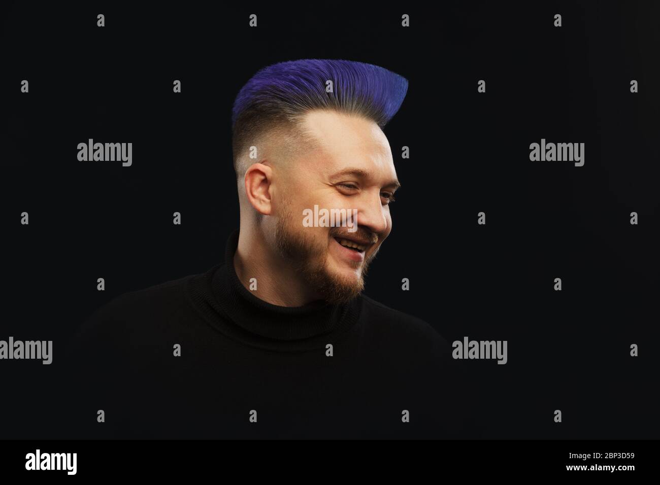 Man with blue or teal hair over dark background. Stock Photo