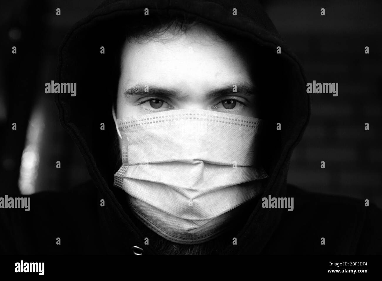 Portrait of young man wearing medical protective face mask for Covid-19 Coronavirus concept. Protect your health. black and white Stock Photo
