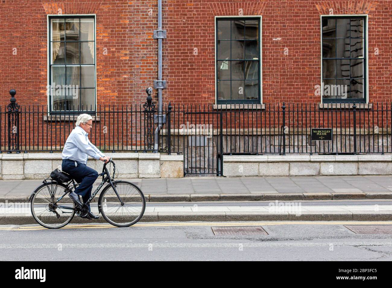 Elderly man on a bike cycling on the road in Dublin City Centre, Ireland Stock Photo