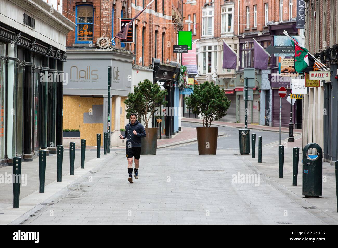 Man jogging through deserted Wicklow Street in Dublin City Centre as the footfall plummets due to coronavirus pandemic. Covid-19 in Ireland. Stock Photo