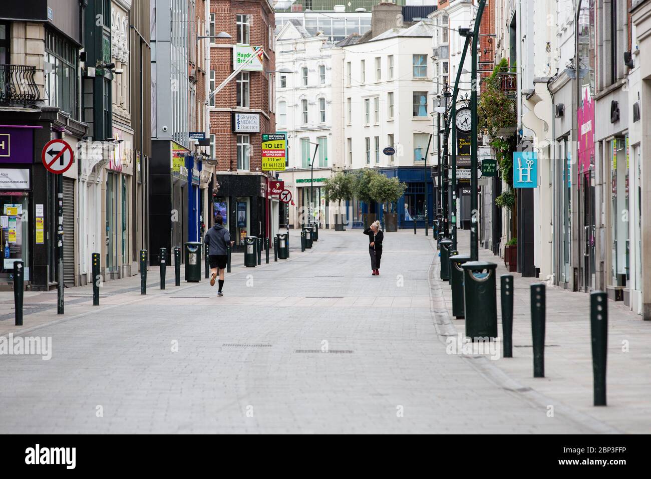 Pedestrians on deserted Grafton Street in Dublin City Centre as the footfall plummets due to coronavirus pandemic. Covid-19 in Ireland. Stock Photo