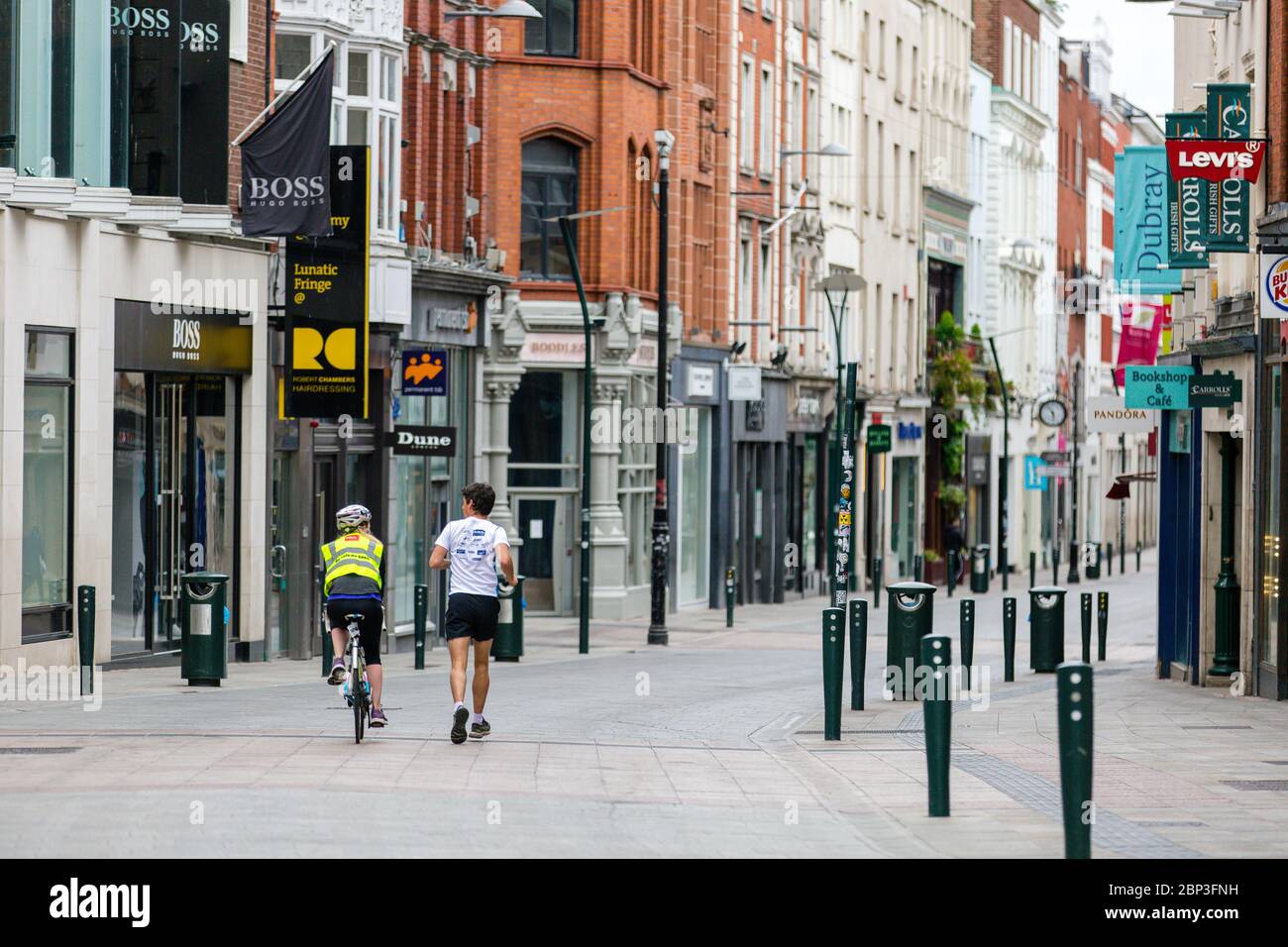 Jogging and cycling through deserted Grafton Street in Dublin City Centre as the footfall plummets due to coronavirus pandemic. Covid-19 in Ireland. Stock Photo