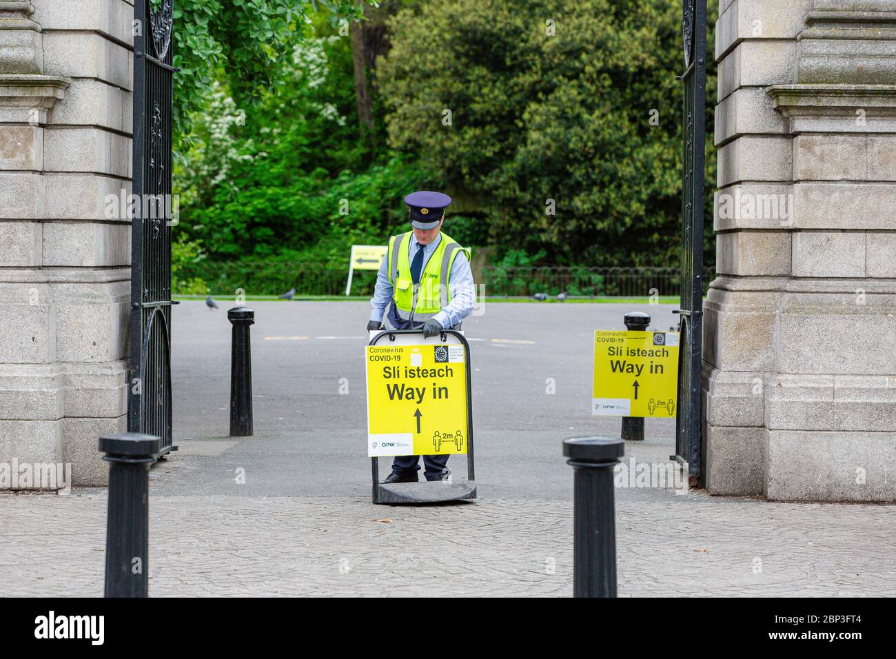 Dublin, Ireland. May 2020. Warden setting up Yellow Coronavirus Covid-19 safety signage at the entrance to the St Stephen's Green Park in Dublin. Stock Photo