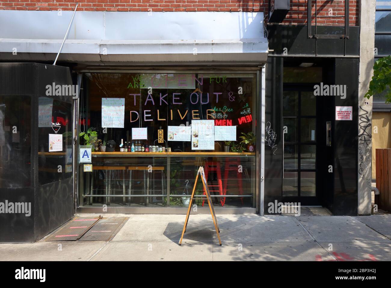 Signage at Mr. Taka restaurant in the Lower East Side indicating they are open for Take Out and Delivery during the coronavirus crisis Stock Photo