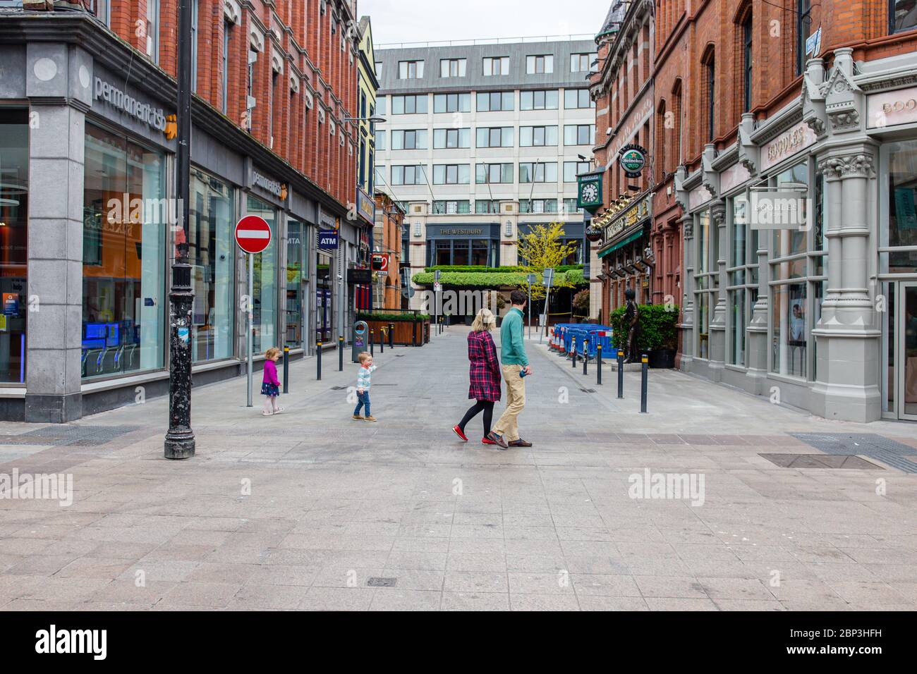 Family sightseeing deserted Grafton Street in Dublin City Centre and its closed businesses, shops and pubs locked due to coronavirus pandemic. Stock Photo