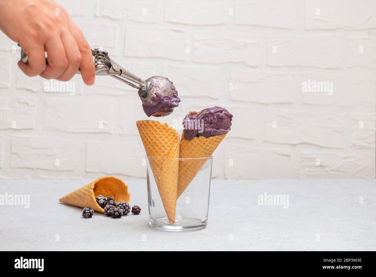Waffle cons with healthy low carb blackberry ice cream and blackberries on neutral kitchen table Stock Photo