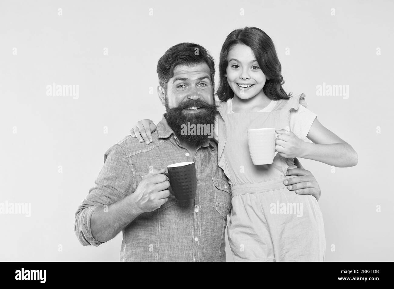 Drink more milk. Little daughter and father hold mugs of milk. Happy