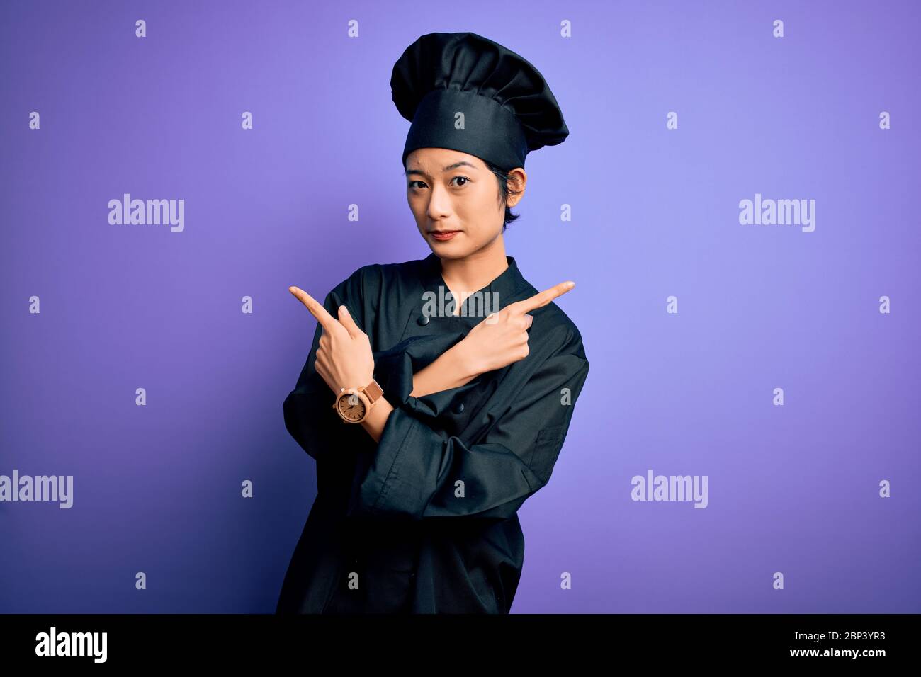 Young beautiful chinese chef woman wearing cooker uniform and hat over ...