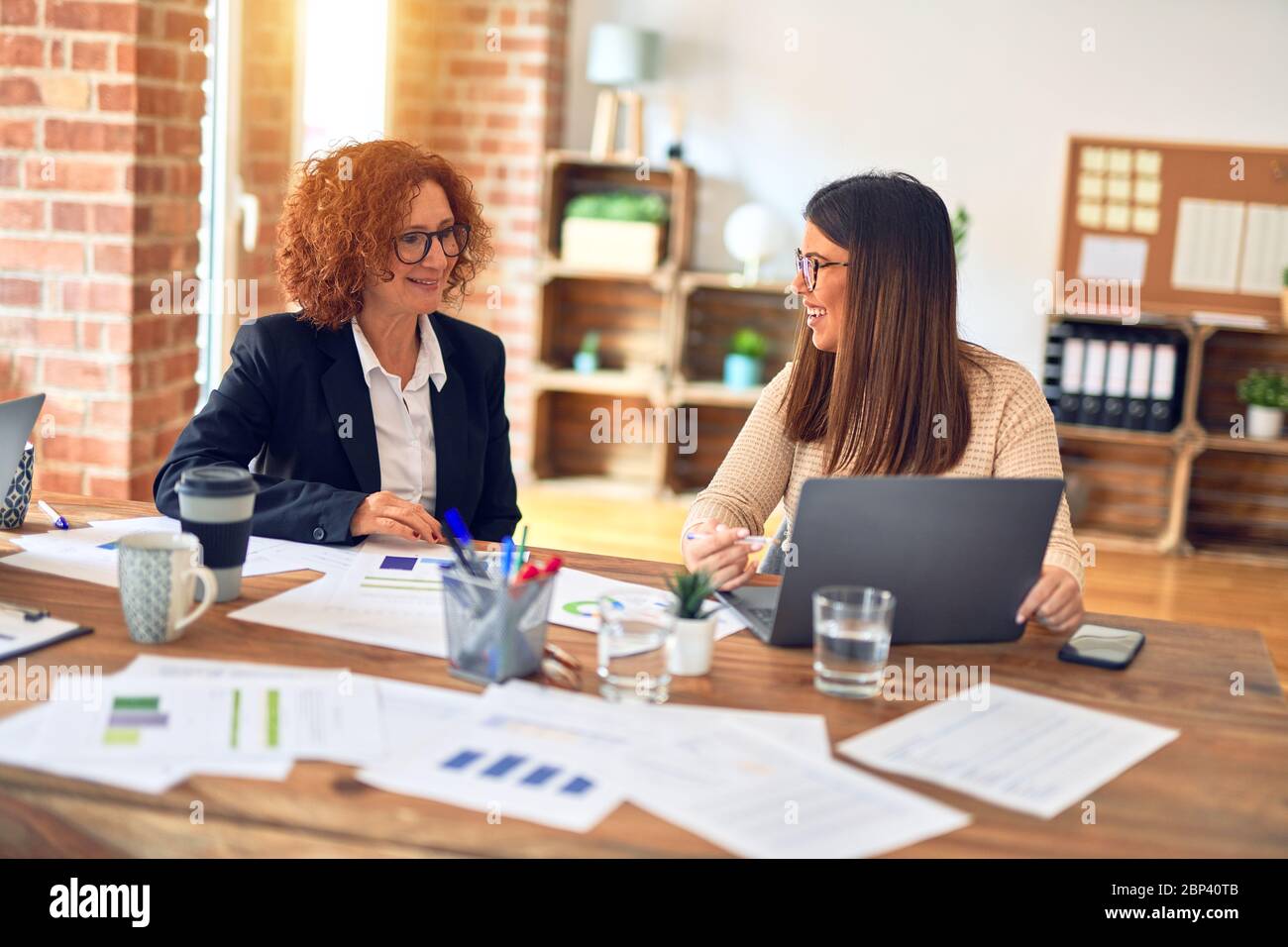 Two beautiful businesswomen smiling happy and confident. Sitting with ...