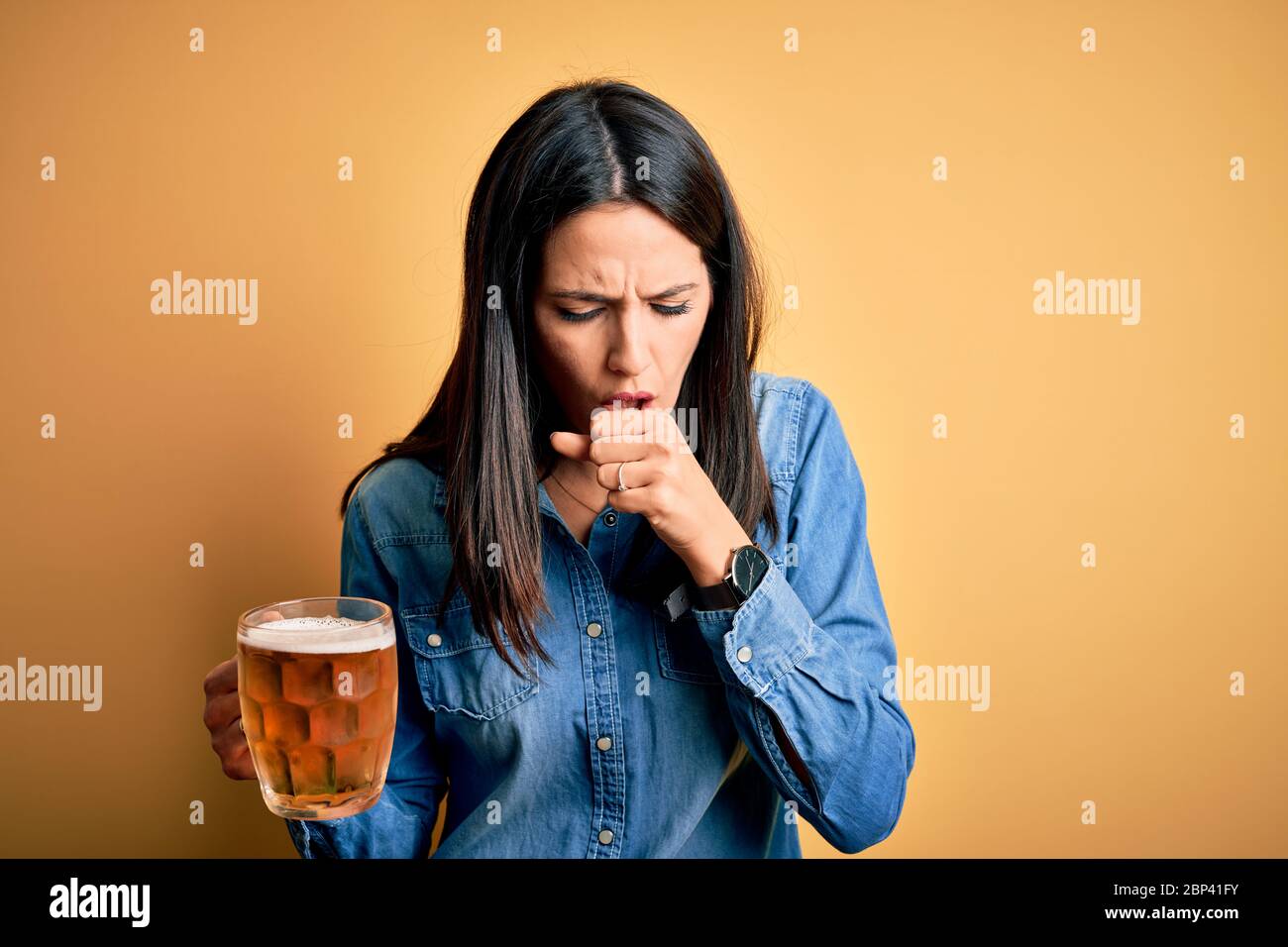 Young woman with blue eyes drinking jar of beer standing over isolated