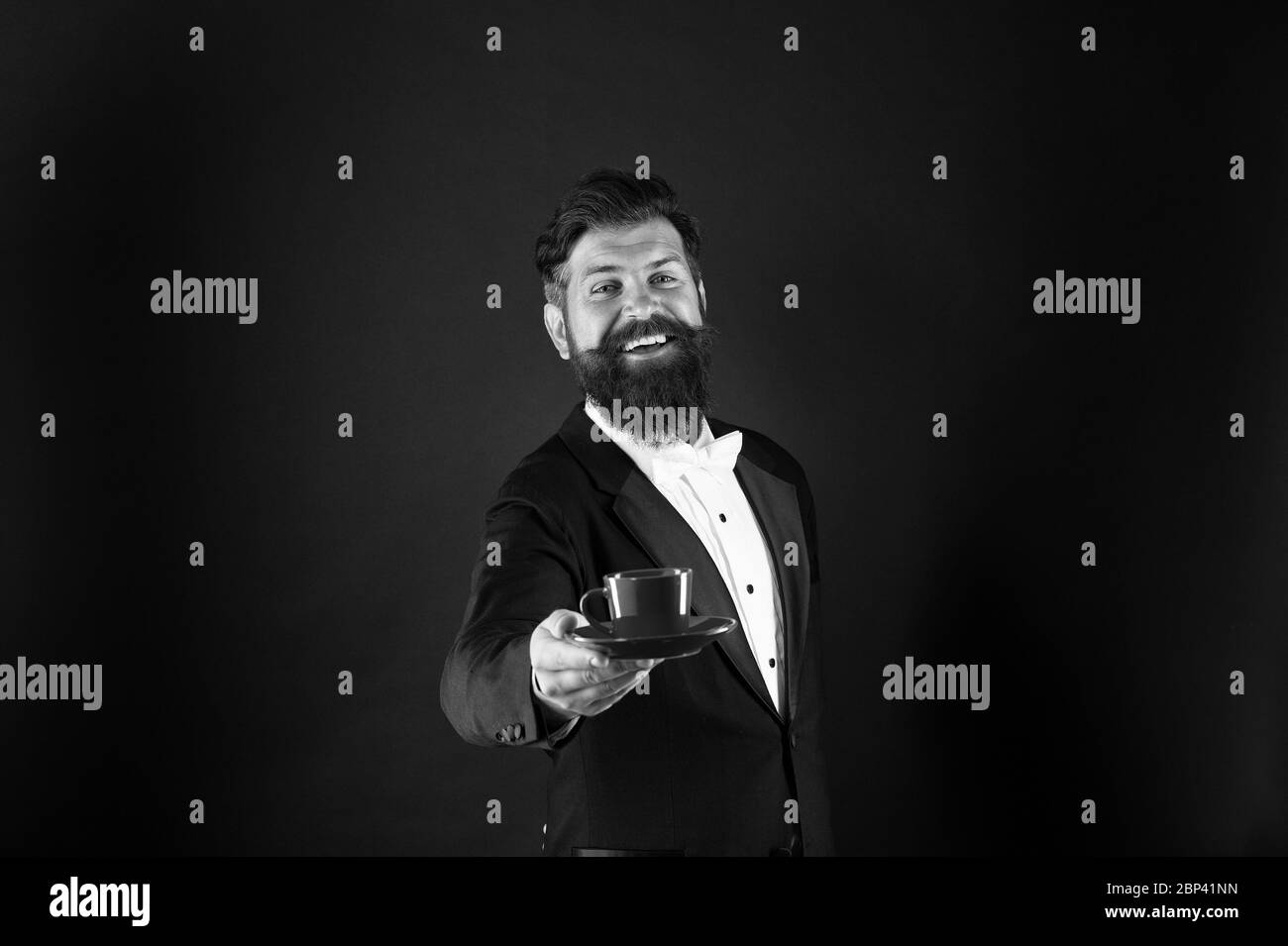 Join my passion for cup of pleasure. Happy waiter offer hot drink. Bearded man give cup of coffee. Get moment of pleasure. Pleasure of coffee inside and outside the cup. Pure pleasure. Stock Photo