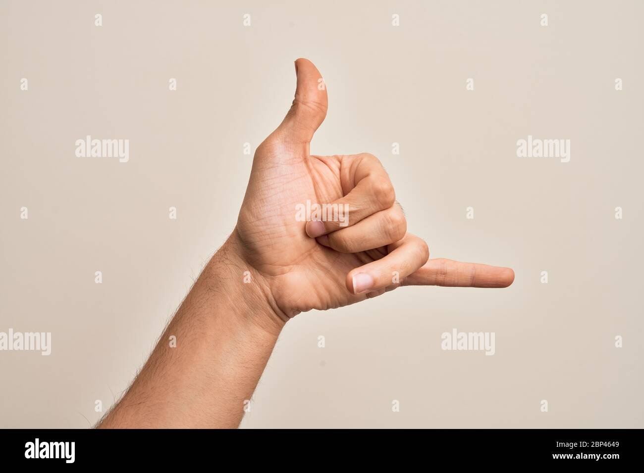 Hand of caucasian young man showing fingers over isolated white background gesturing Hawaiian shaka greeting gesture, telephone and communication symb Stock Photo