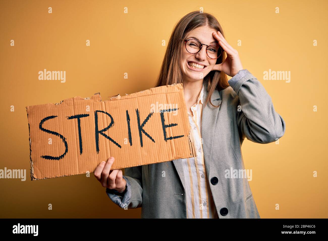 Young beautiful redhead woman holding banner with strike message over ...