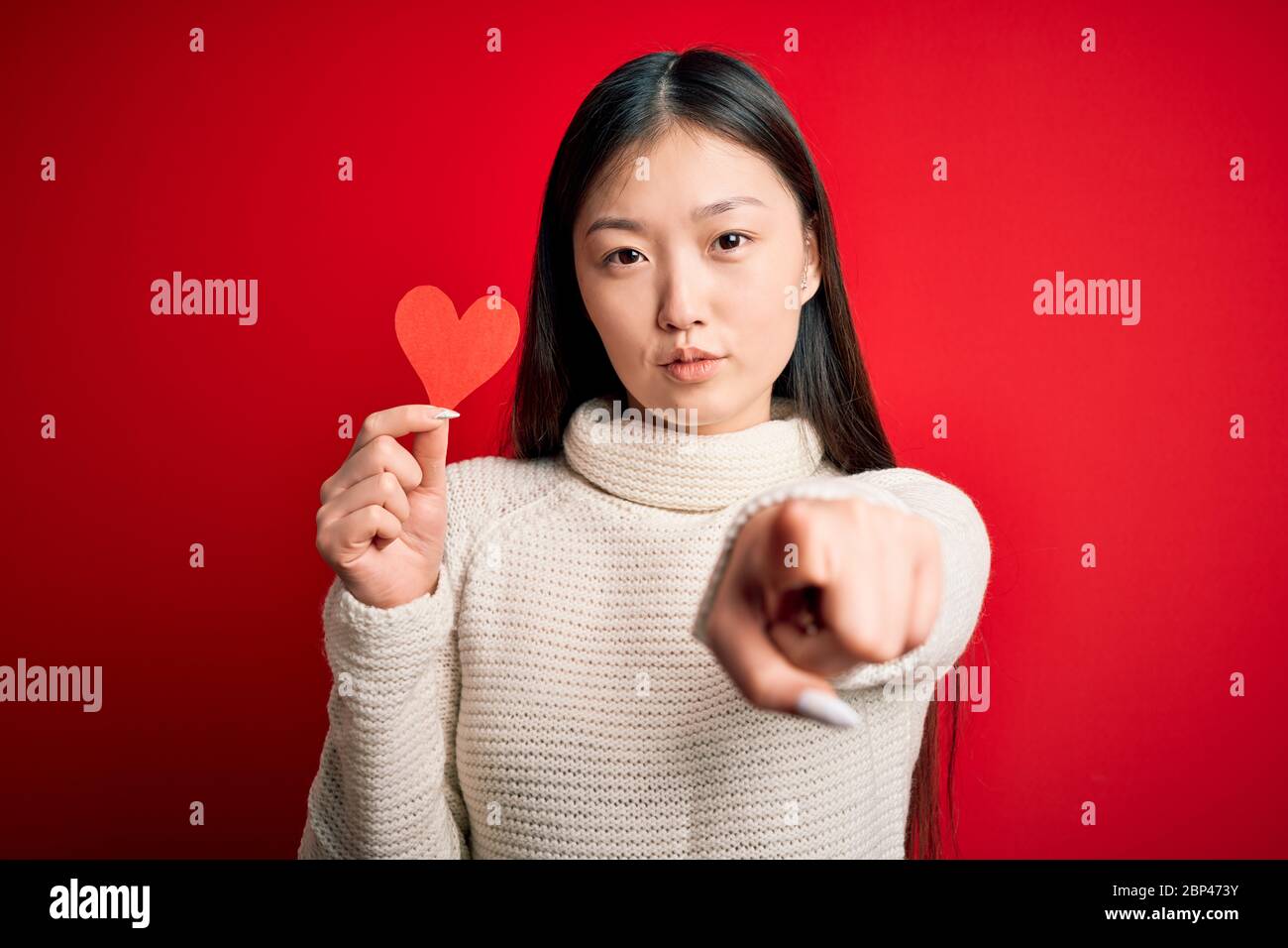 Young asian woman holding romantic red heart paper shape over red ...