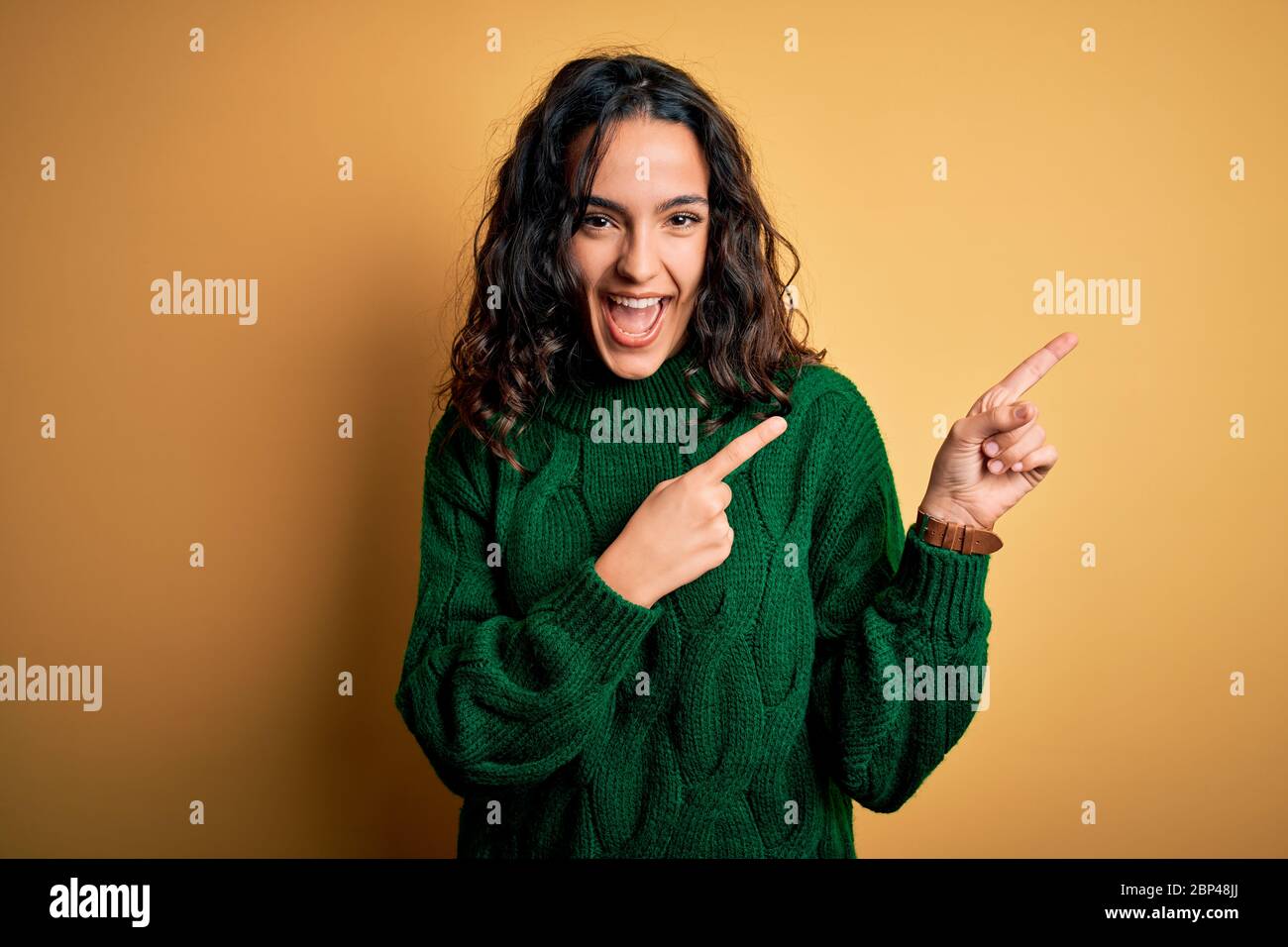 Young beautiful woman with curly hair wearing green casual sweater over ...
