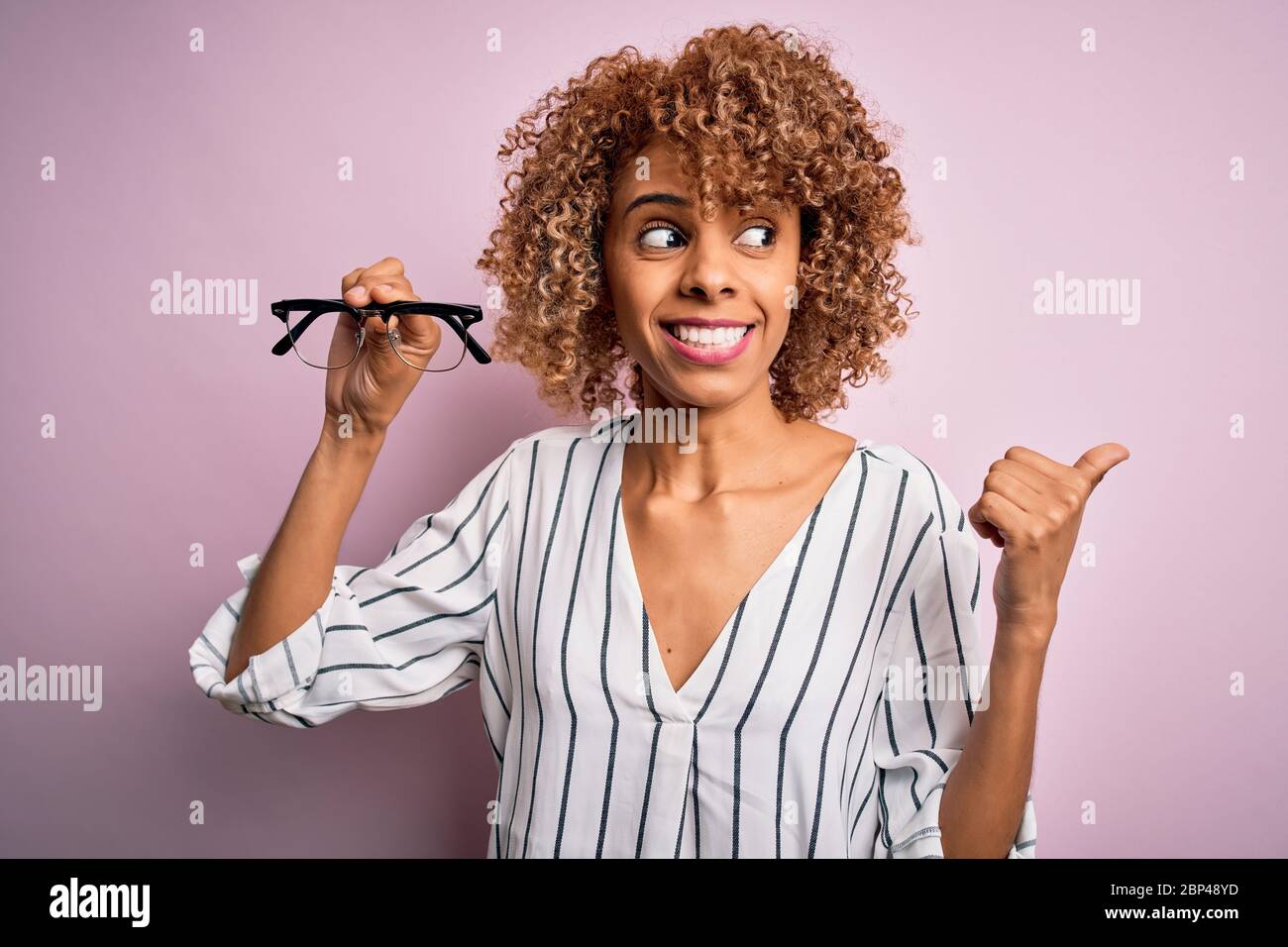 African american optical woman with curly hair holding glasses over ...