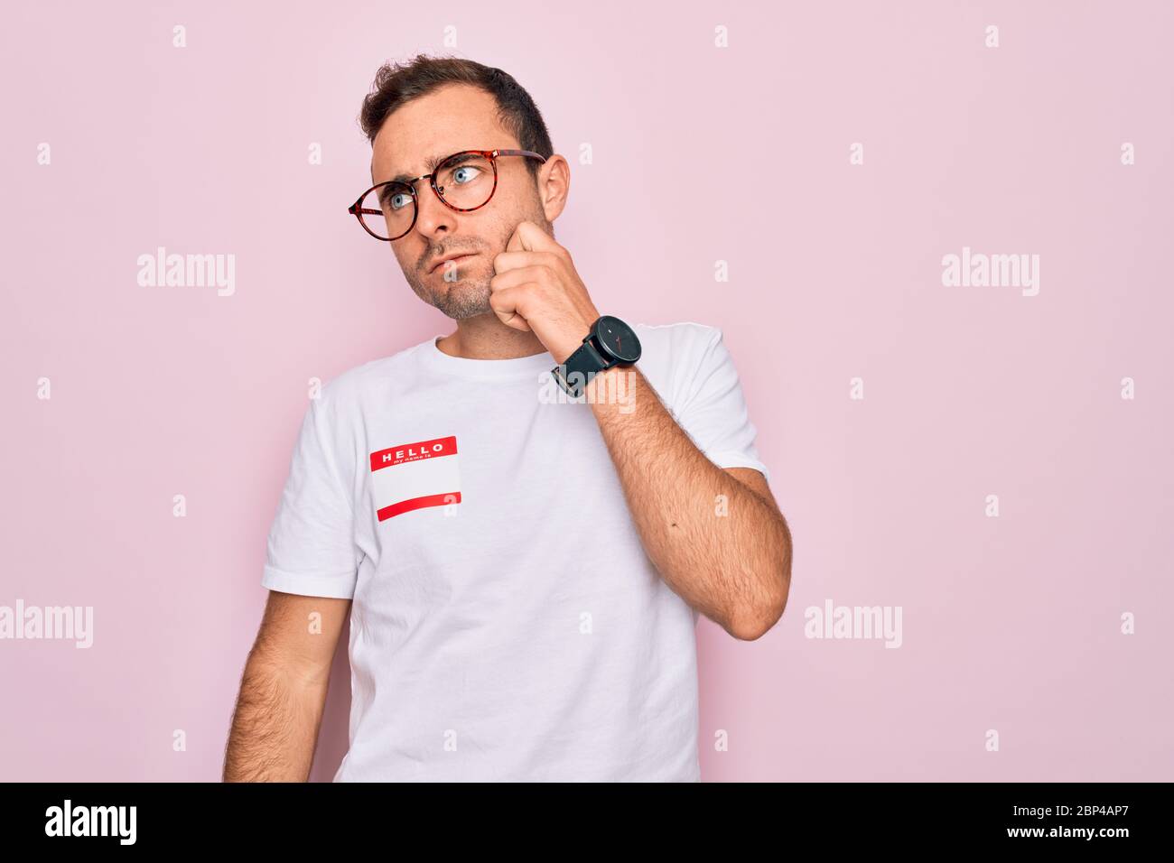 Handsome man with blue eyes wearing sticker with hello my name is ...