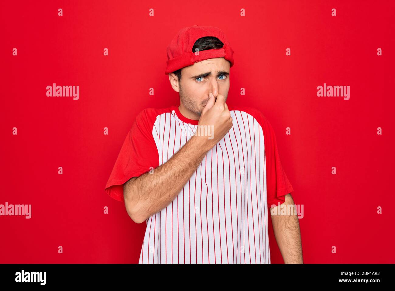 Young handsome sporty man with blue eyes wearing striped baseball t