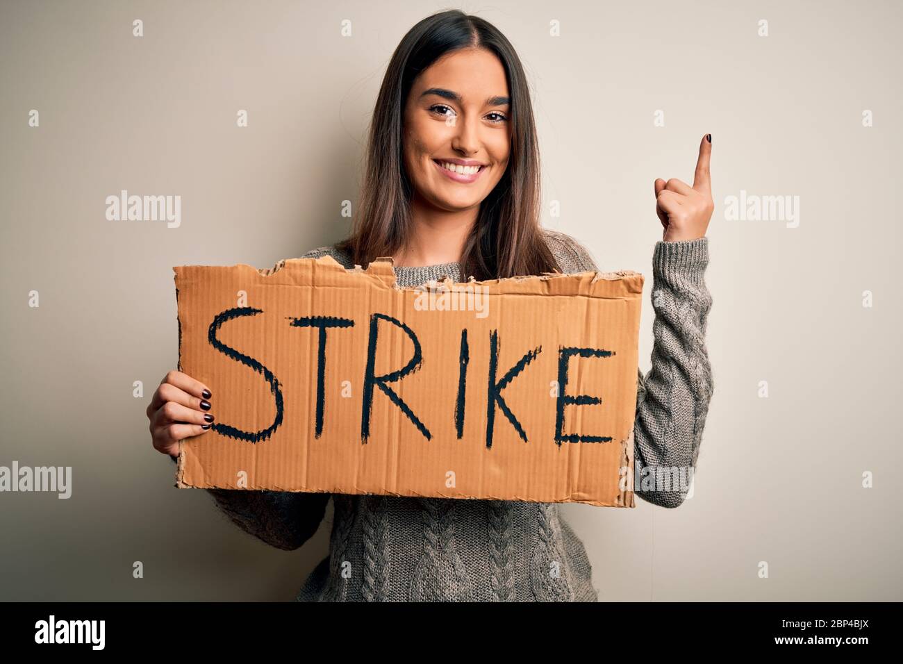Young beautiful brunette activist woman protesting holding poster with ...