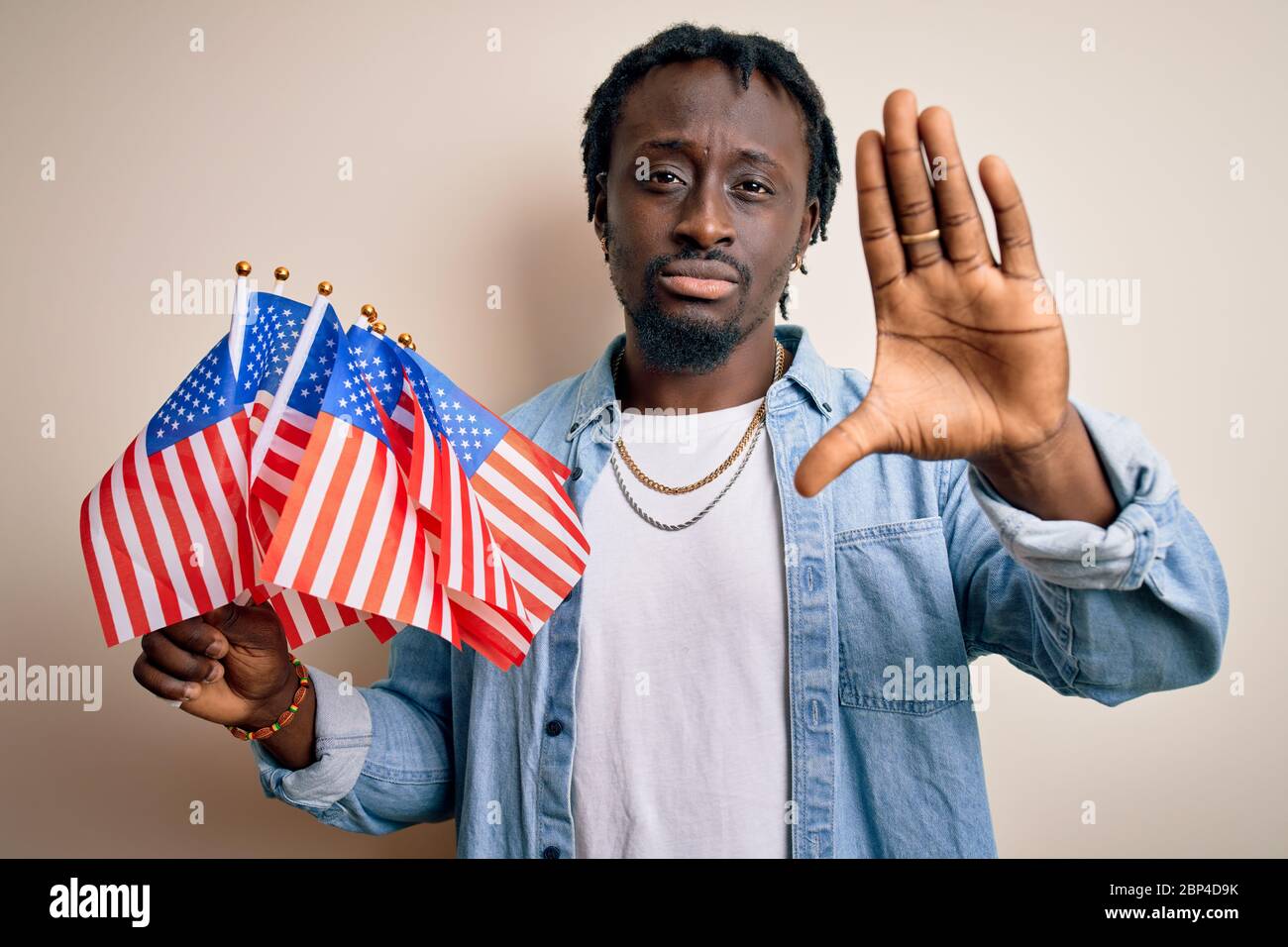 Young african american patriotic man holding united states flags over ...