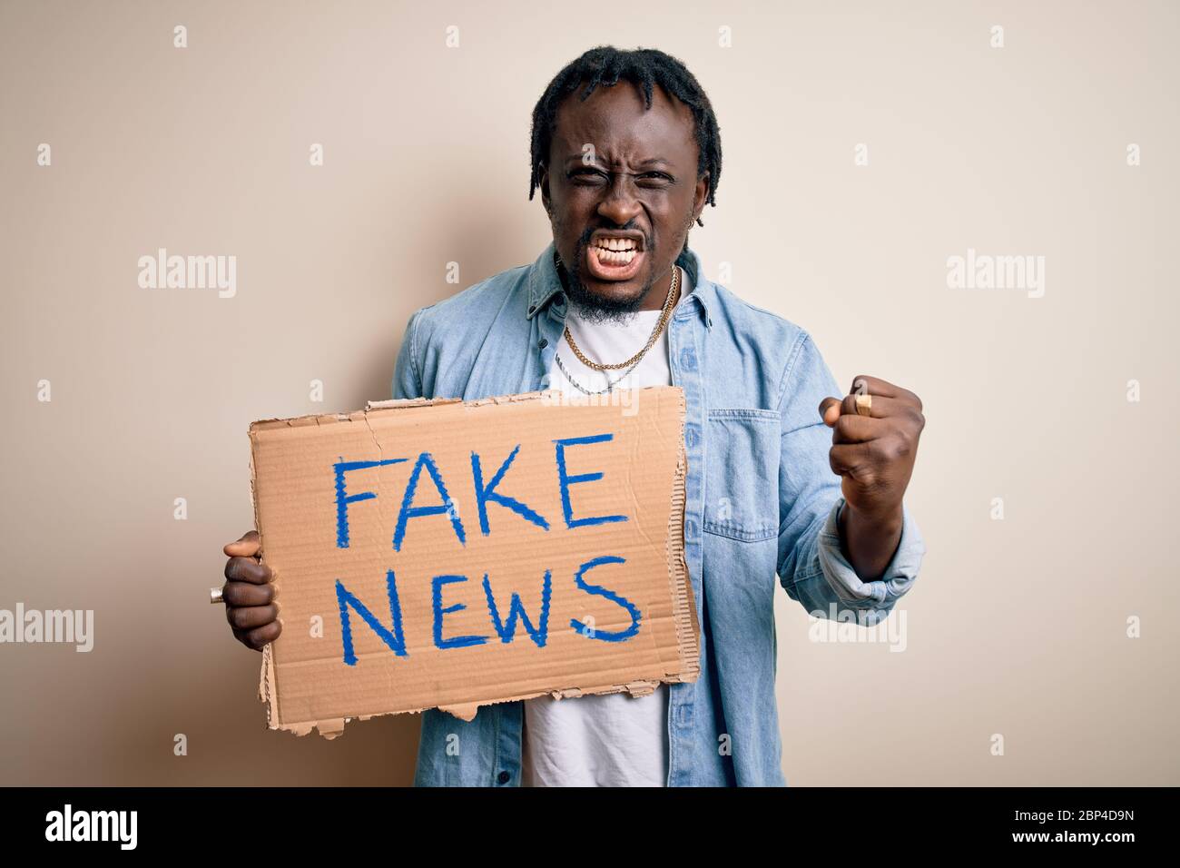 Young african american man holding banner with fake news message over ...