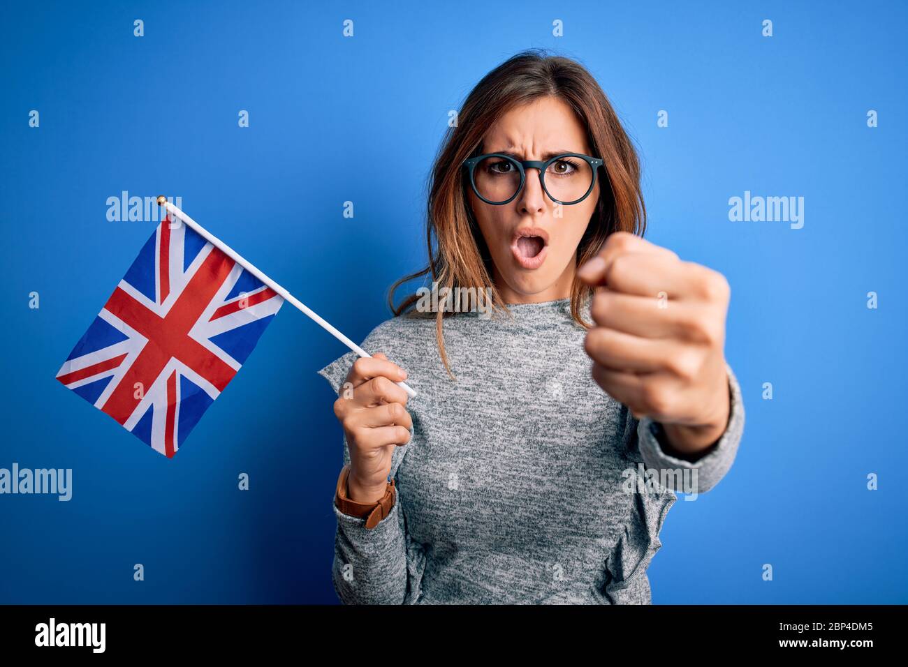 Young beautiful brunette patriotic woman holding united kingdom flag on brexit referendum annoyed and frustrated shouting with anger, crazy and yellin Stock Photo