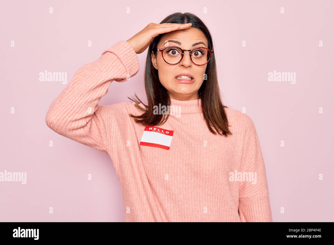 Young beautiful brunette woman wearing sticker with hello my name is ...
