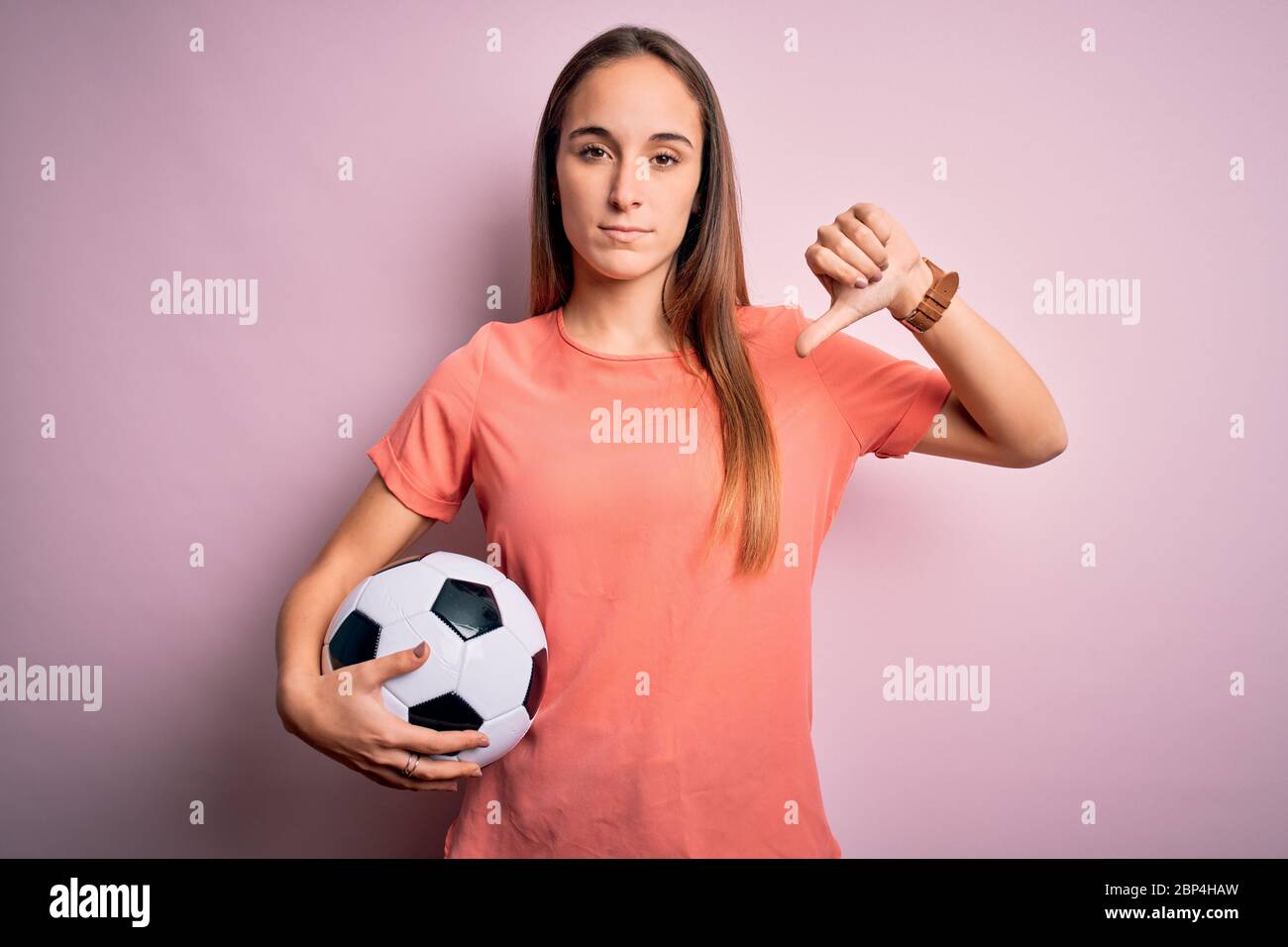 Young beautiful player woman playing soccer holding football ball over ...