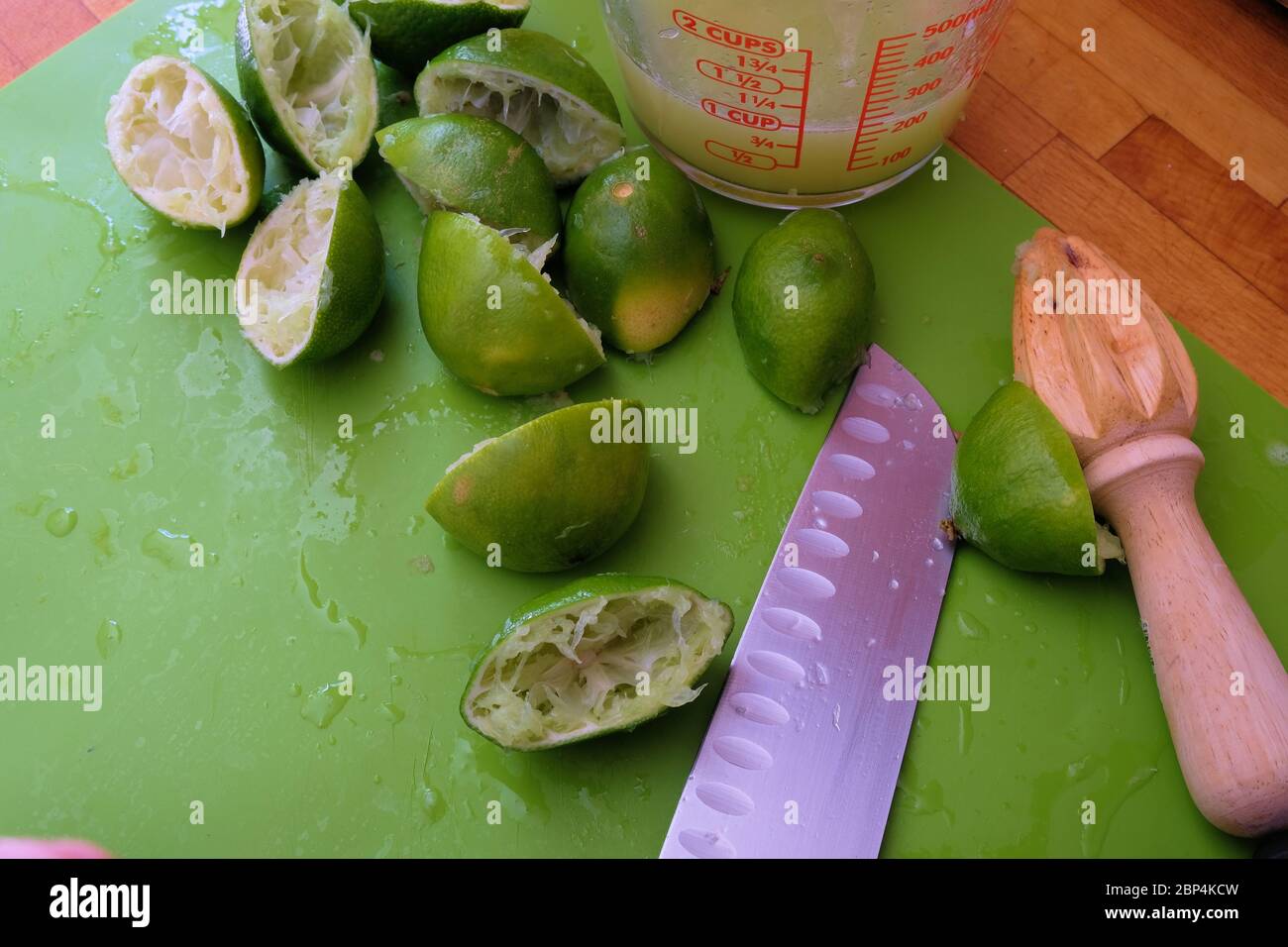 Lime juice in a glass measuring cup with juiced limes cut in half on a