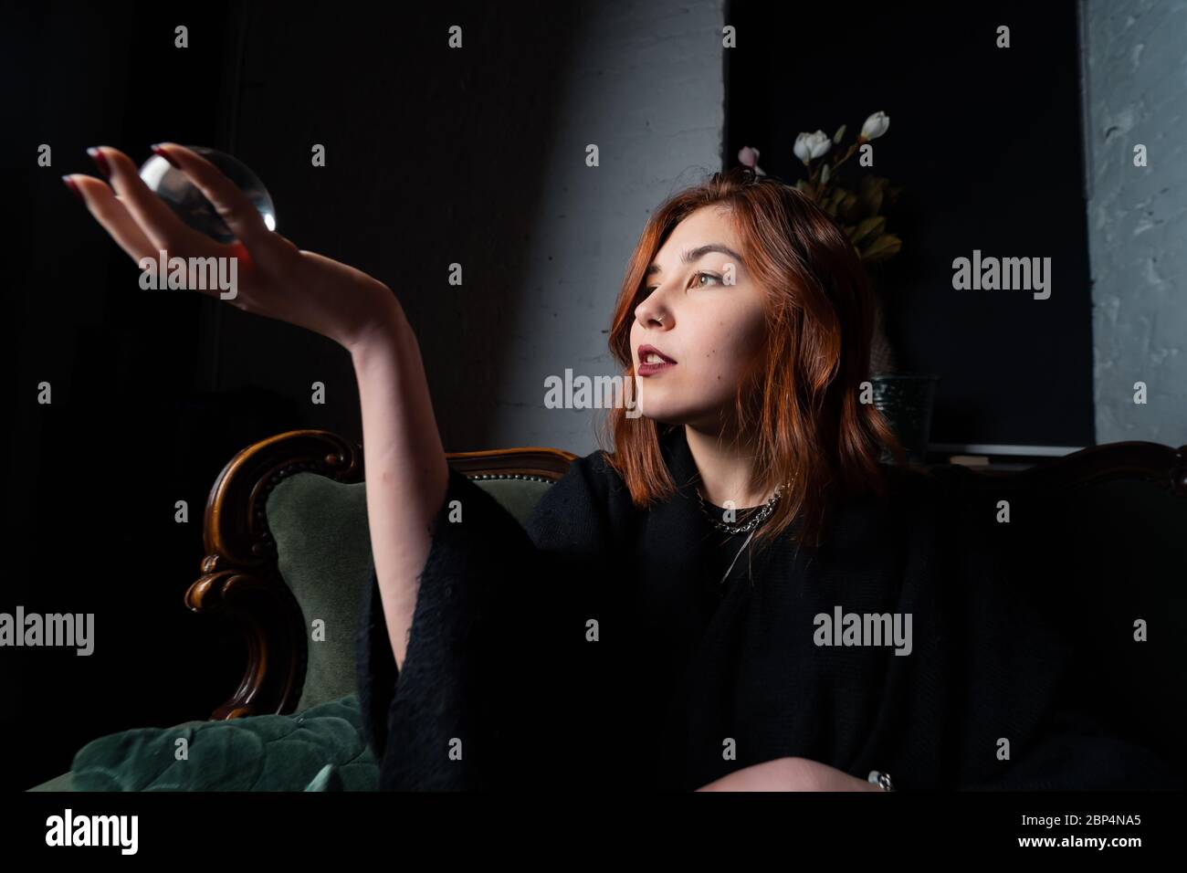 Woman in black suit holding crystal ball Stock Photo - Alamy