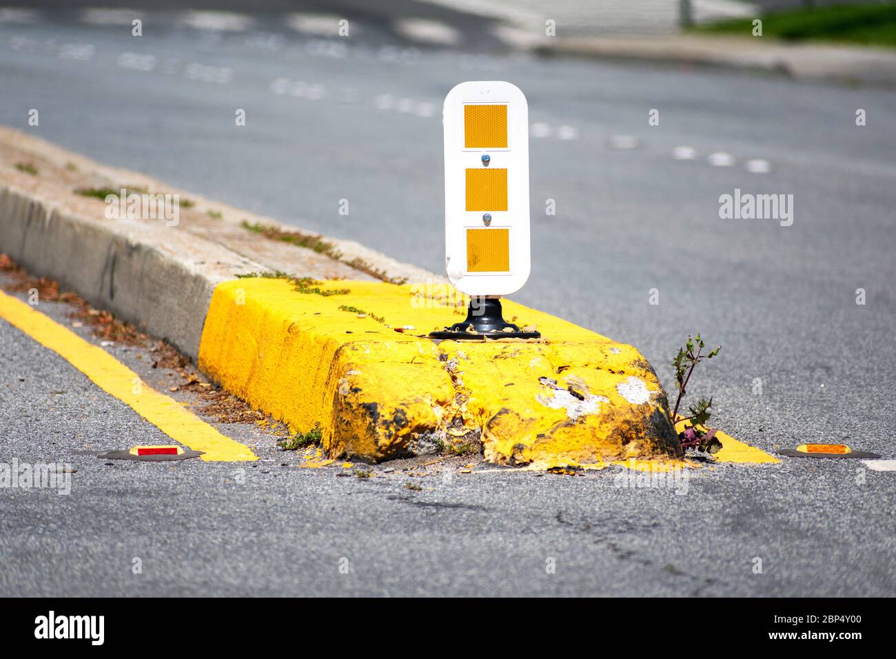 Dividing median curb on empty road with white and yellow warning