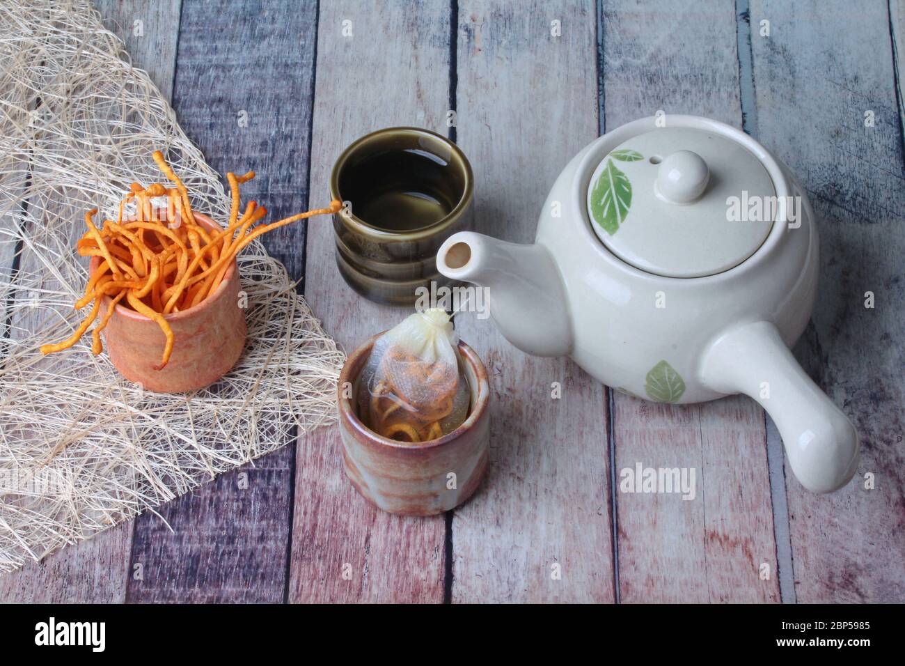 Golden cordyceps mushroom in cup ,herbal tea bag of  golden cordyceps militaris and tea in cup served on wood Stock Photo