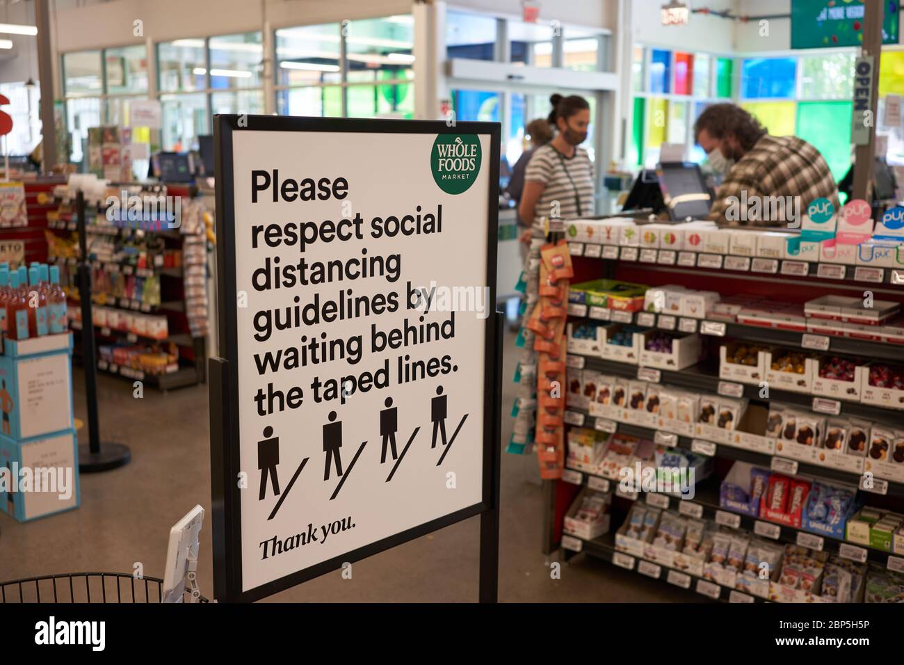 The sign at the checkout area in a Whole Foods Market reminds shoppers to respect social distancing guidelines during COVID-19 pandemic on 5/15/2020. Stock Photo