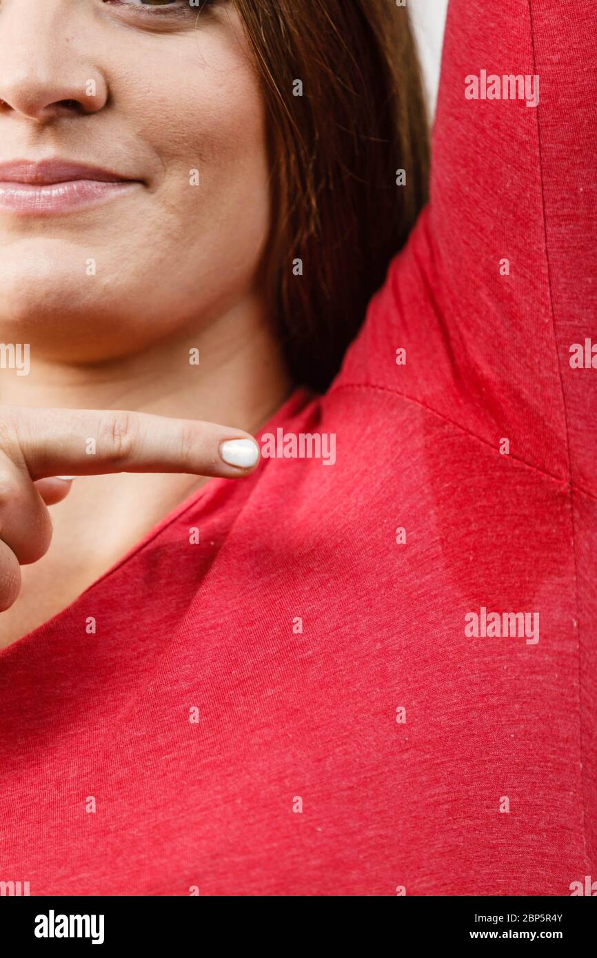 Sweaty girl pointing at wet stain under arm. Bad sweating problem Stock