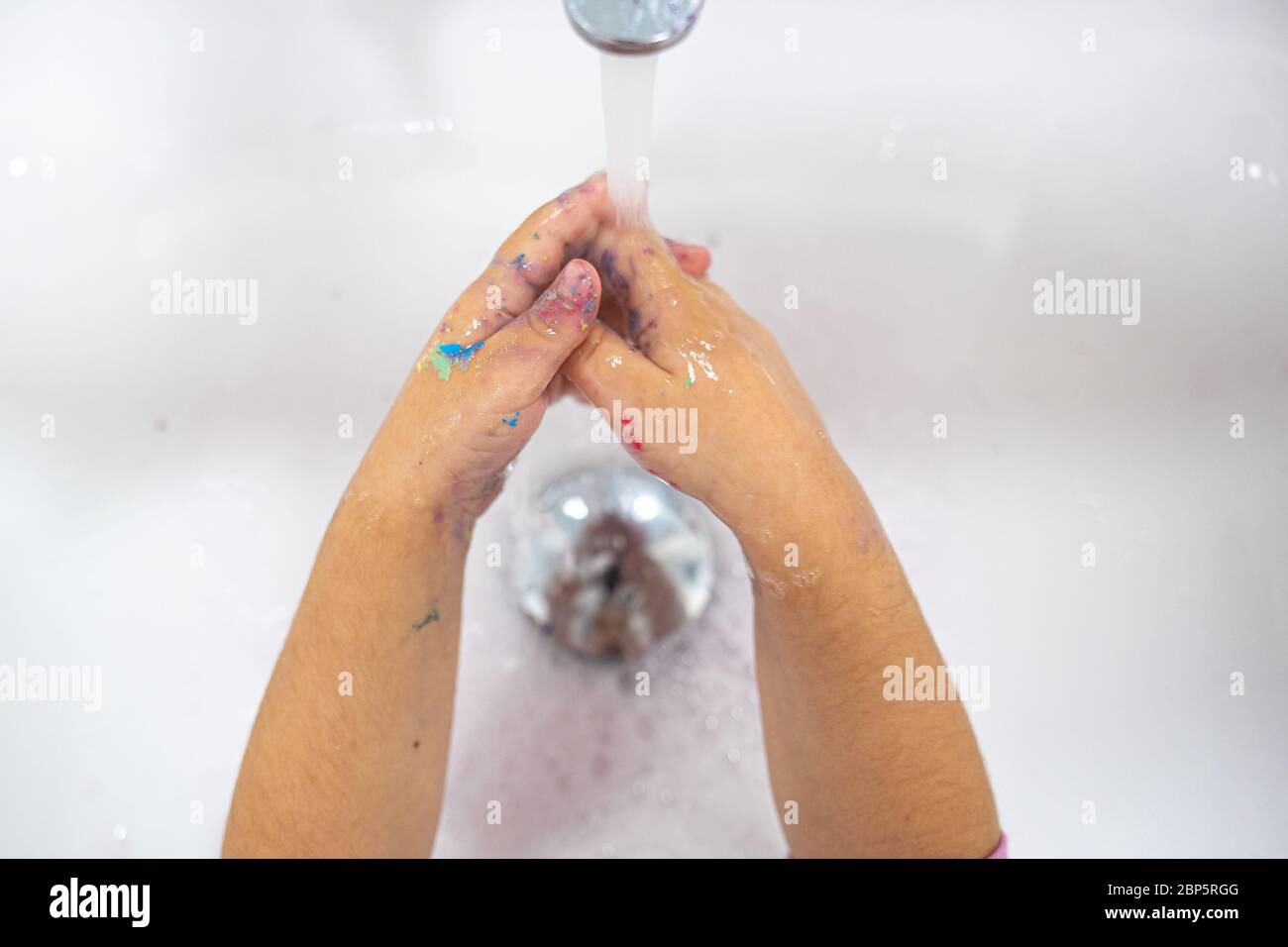 Washing hands on a white sink with water, child hands Stock Photo