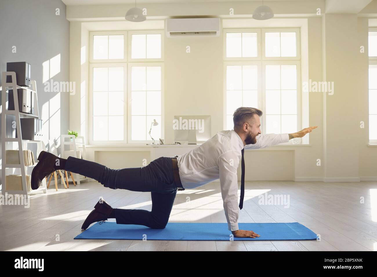 Businessman doing yoga exercises while lying in the office. Stock Photo