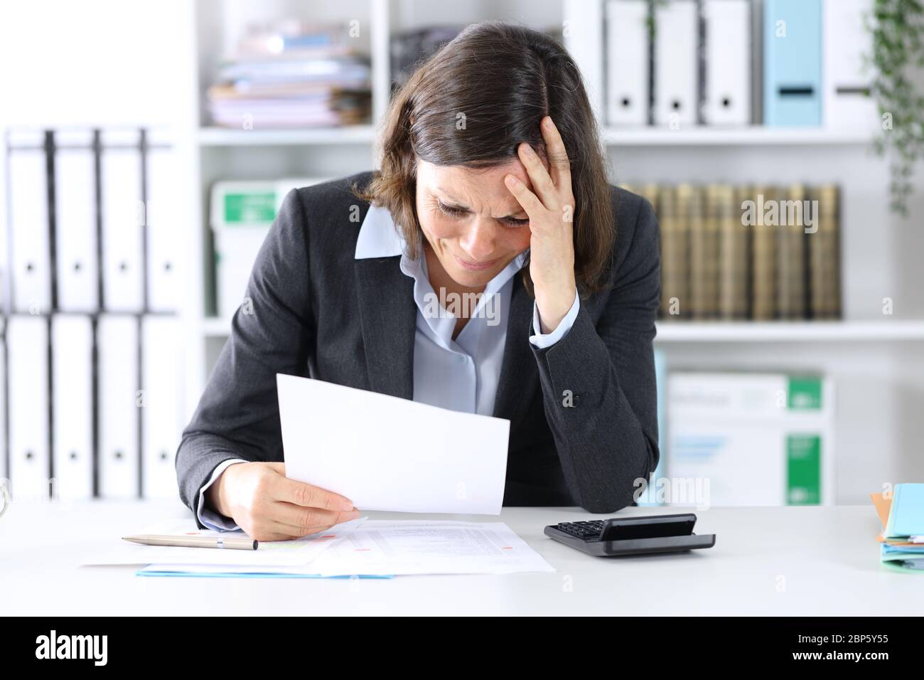 Sad executive lady complaining about bad results sitting on a desk at