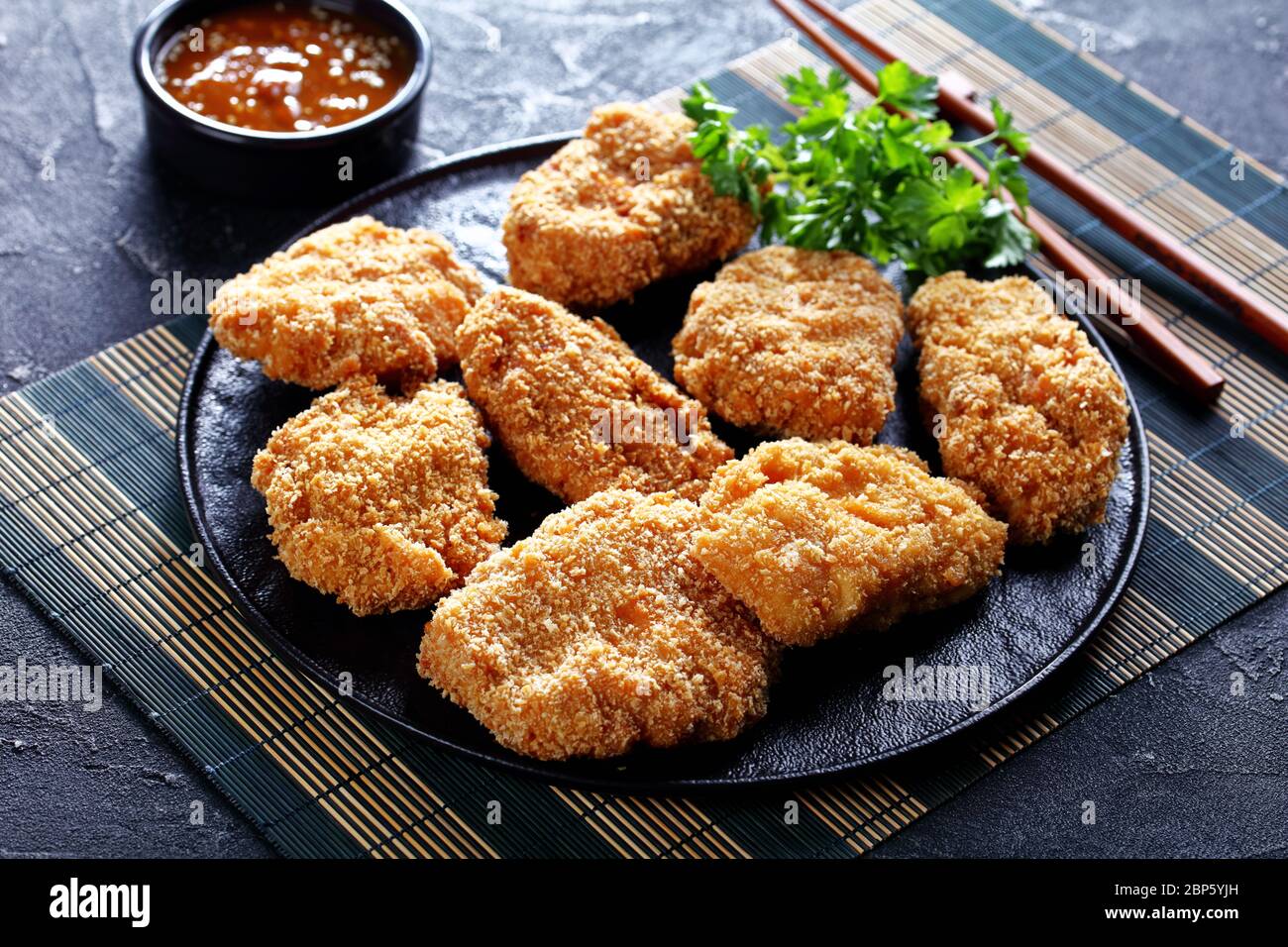 close-up of HireKatsu, Japanese pork cutlets on a black plate with delicious flavourful miso sauce on a bamboo mat Stock Photo