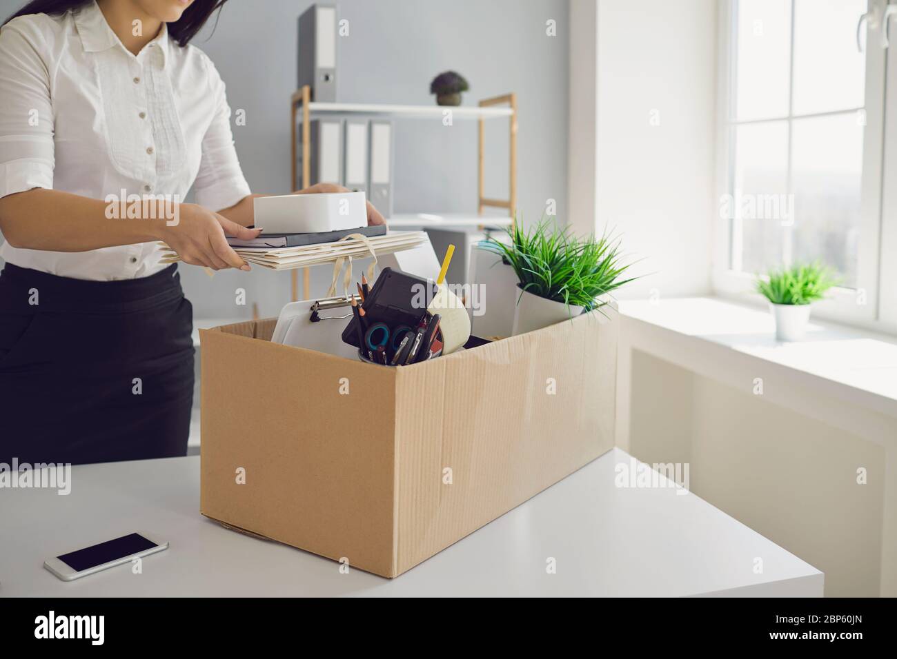 Unemployment Dismissed business woman upset with a cardboard box leaves the workplace from the office of the company. Stock Photo