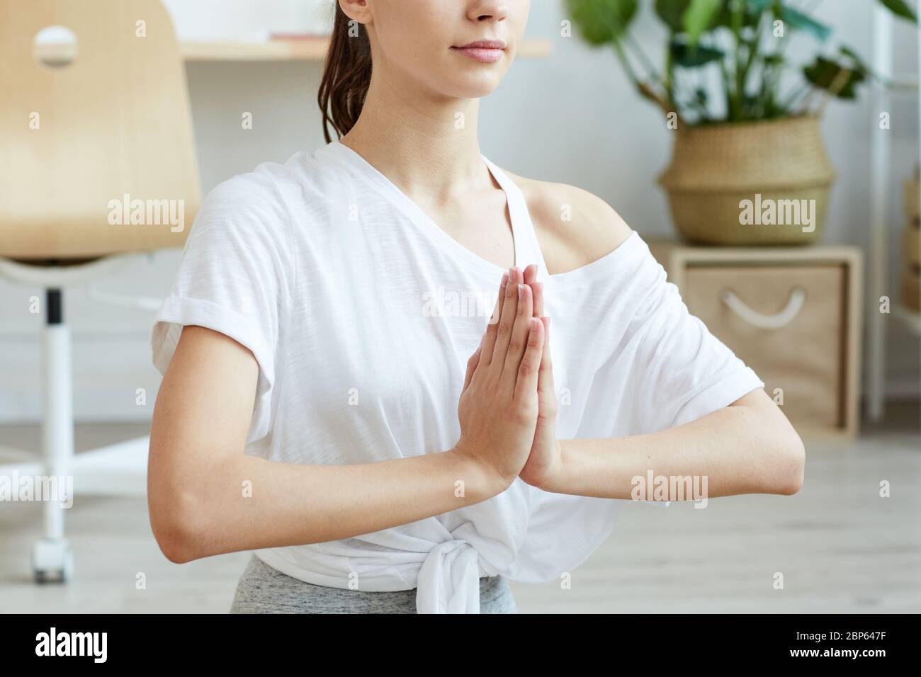 Cropped portrait of contemporary young woman doing yoga at home while sitting in lotus position, copy space Stock Photo