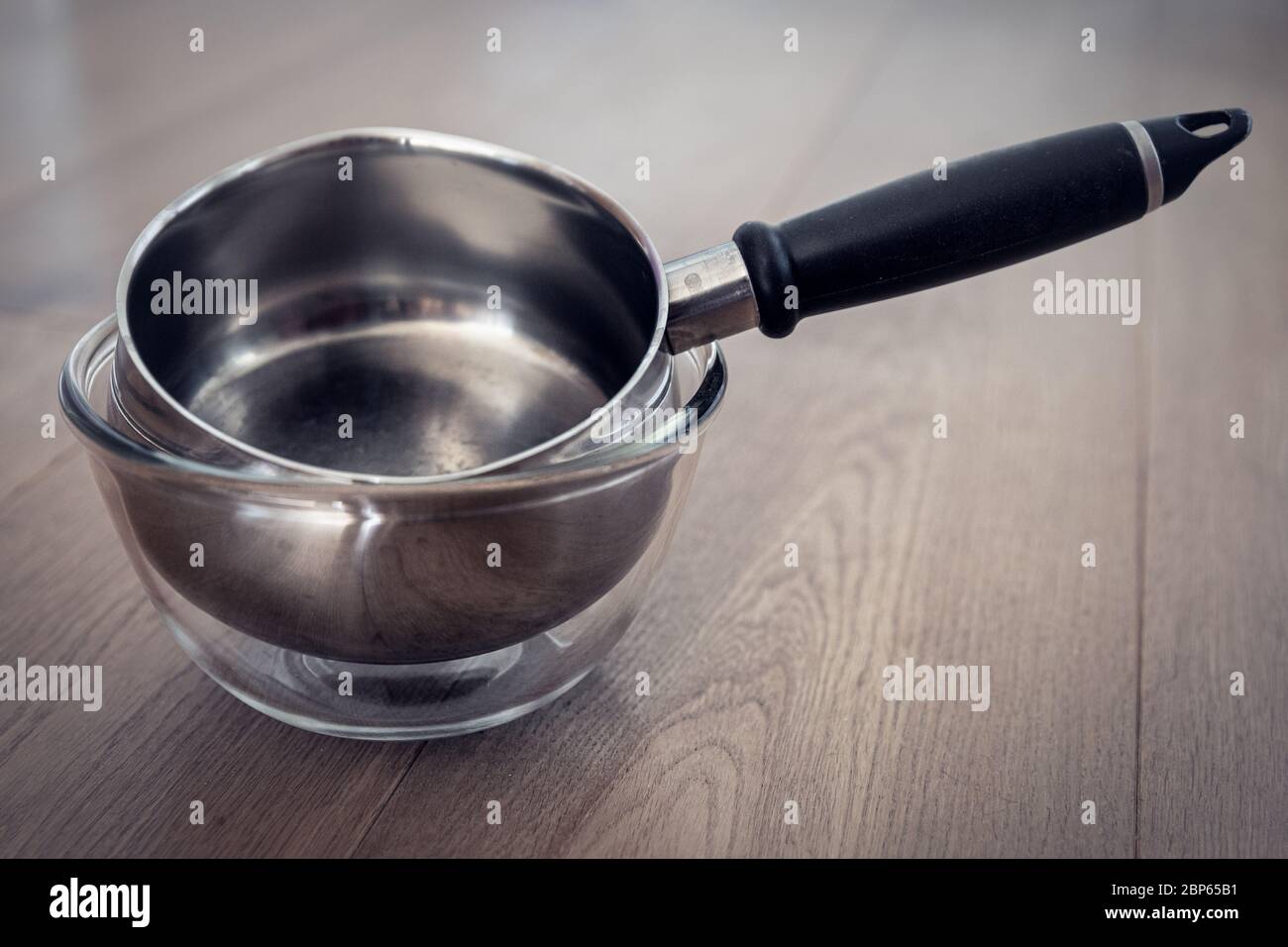 A silver saucepan in a glass bowl Stock Photo
