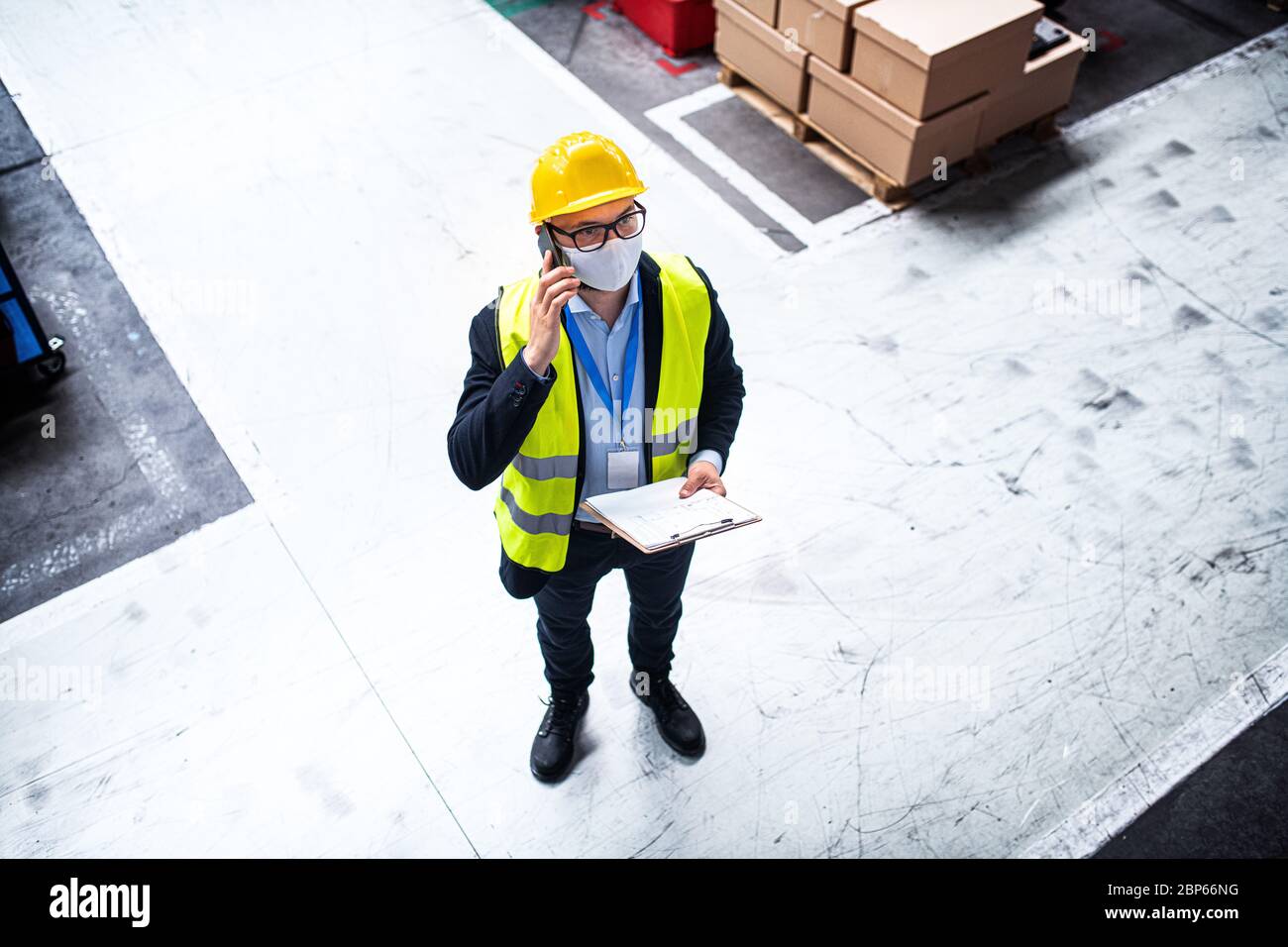 Technician or engineer with protective mask and helmet working in industrial factory. Stock Photo