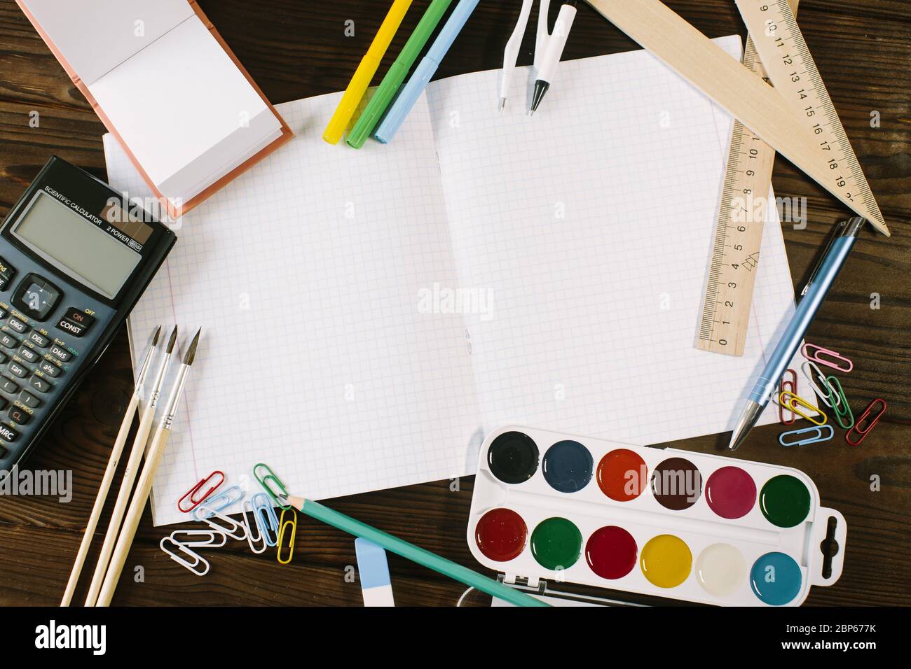 Layout of notebooks, pencils, markers and clips on a wooden background ...
